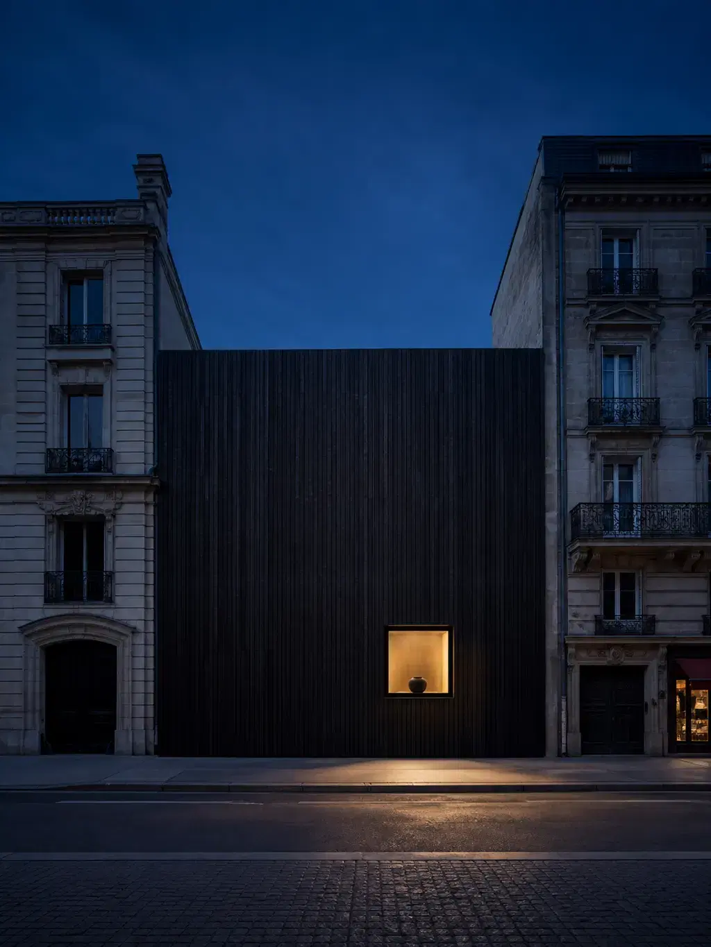 Façade monolithique noire de nuit avec niche lumineuse et vase