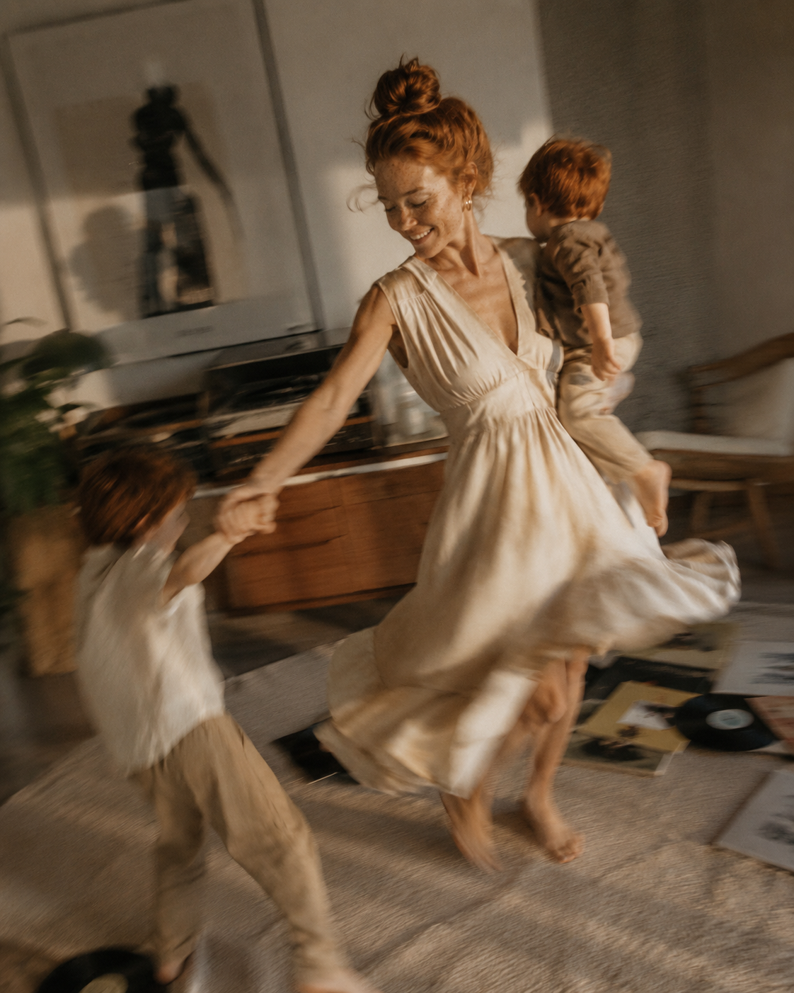 Mère en robe blanche dansant avec ses deux enfants roux – flou de mouvement et vinyles au sol