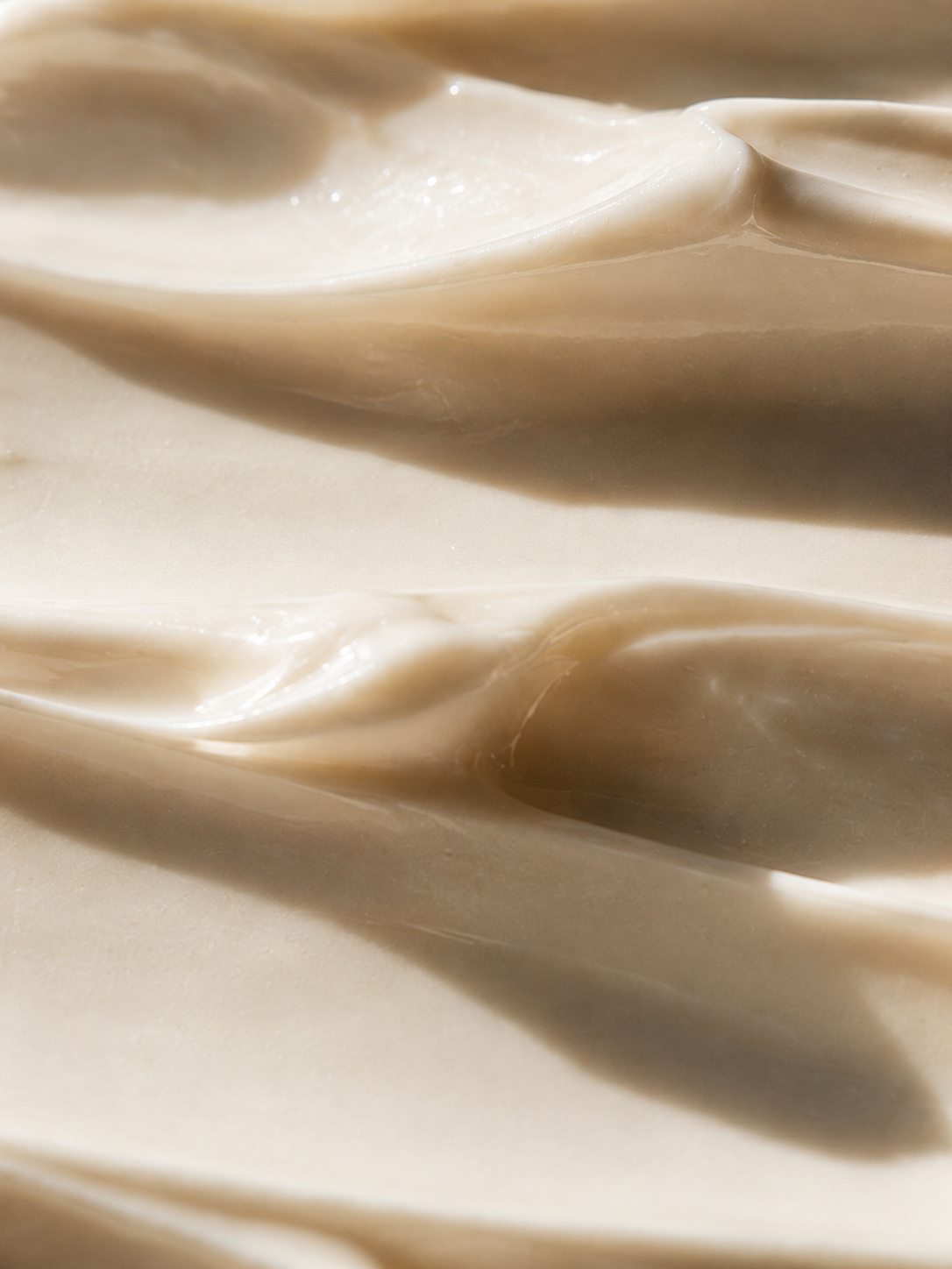 Macro texture crème en vagues beige crème – ondulations soyeuses, formule onctueuse, fond uni