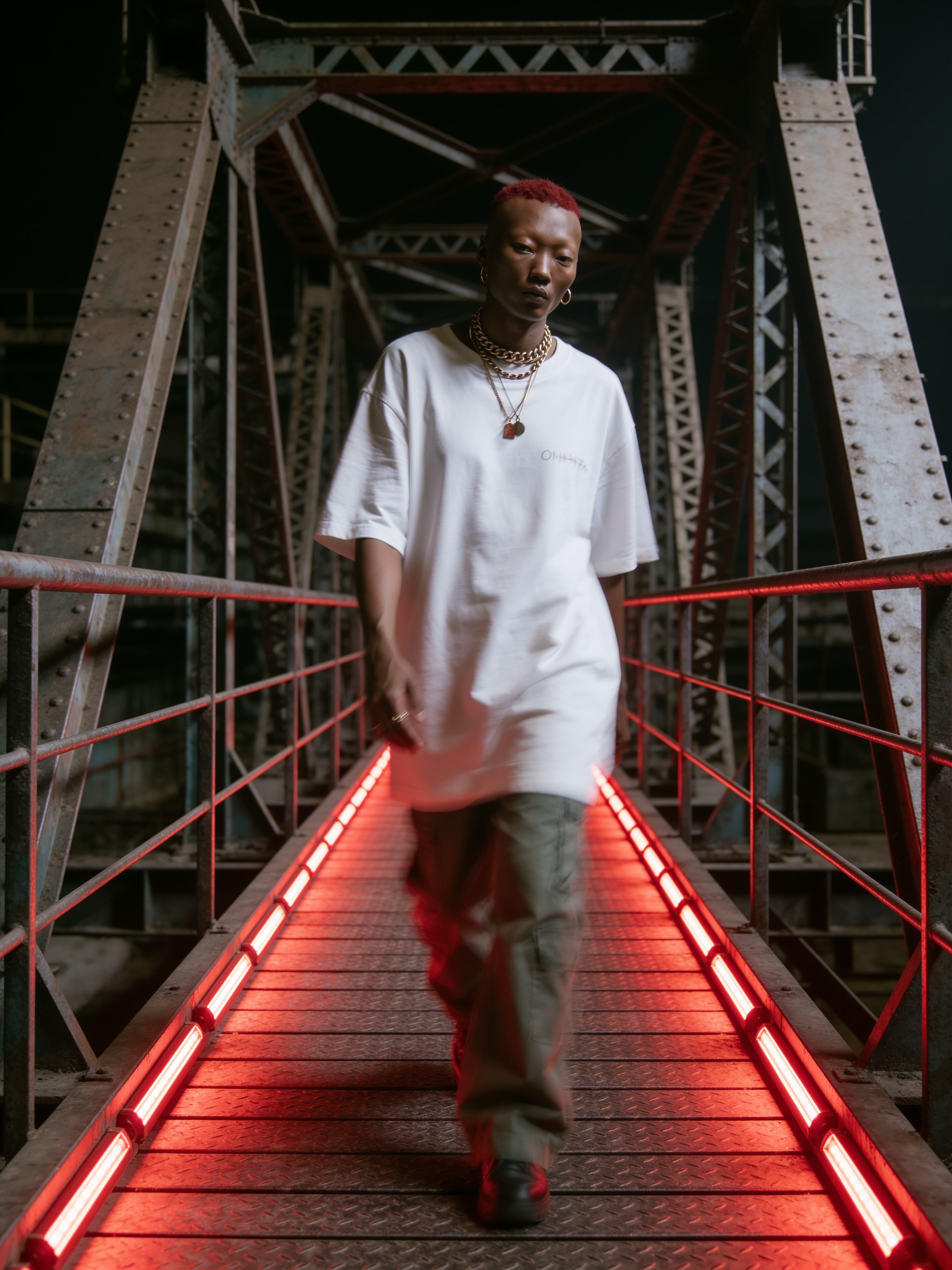 Homme aux cheveux rouges marchant vers l'objectif sur une passerelle industrielle aux rails LED rouges