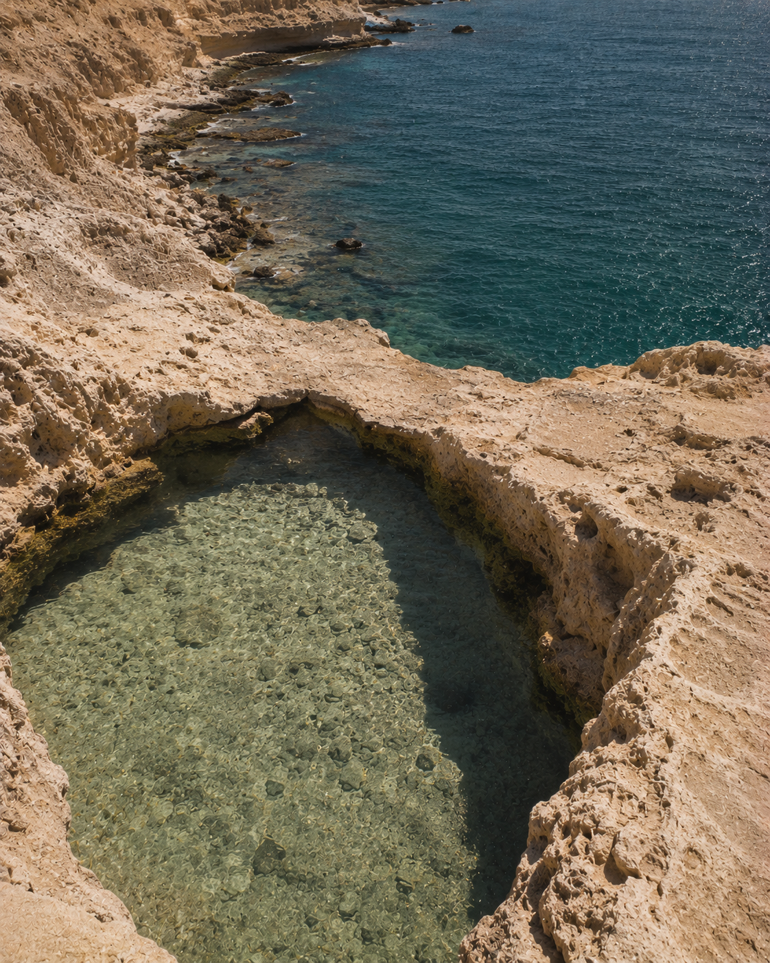 Piscine naturelle creusée dans rocher calcaire – eau turquoise et mer bleue en contrebas