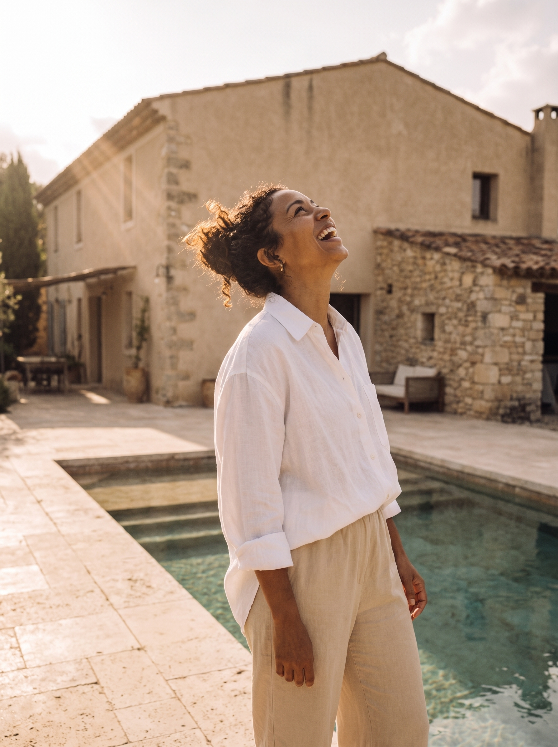 Femme noire en lin blanc et beige au bord d'une piscine de bastide