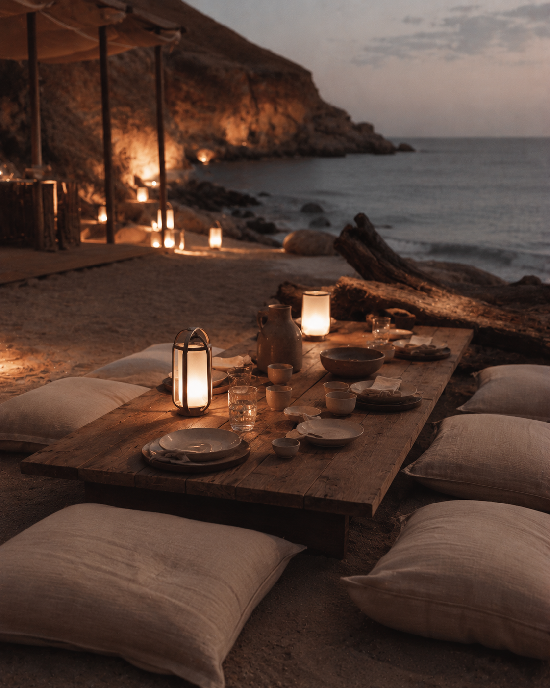 Dîner romantique sur sable de plage au crépuscule – table basse, coussins lin, lanternes