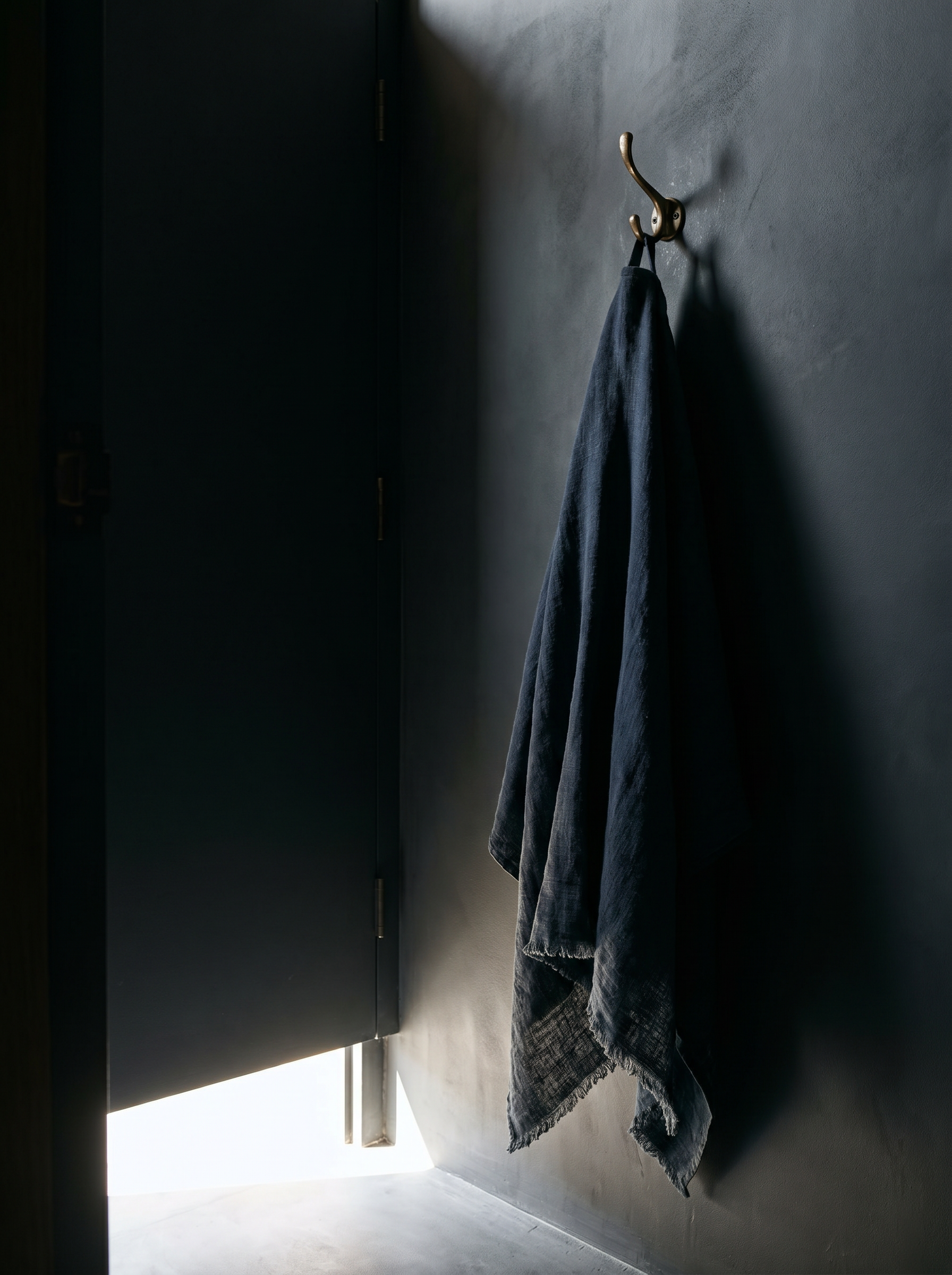 Serviette en lin marine accrochée à un crochet sur mur sombre