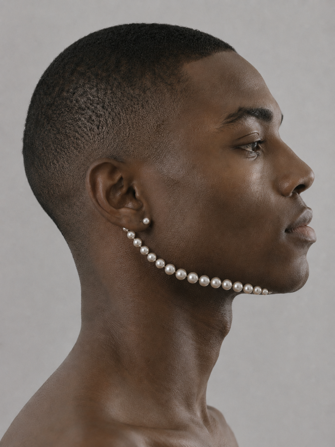 Portrait masculin de profil, rang de perles courant de l'oreille à la mâchoire comme un bijou ancré