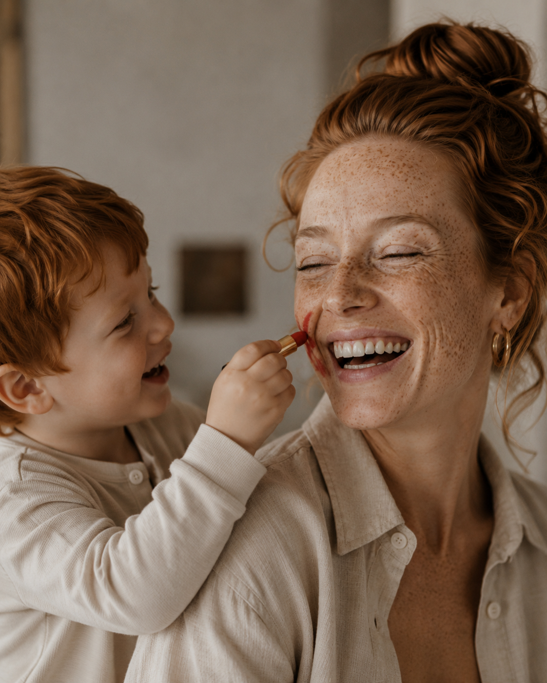 Enfant roux appliquant du rouge à lèvres sur le nez de sa mère riante – gros plan complice
