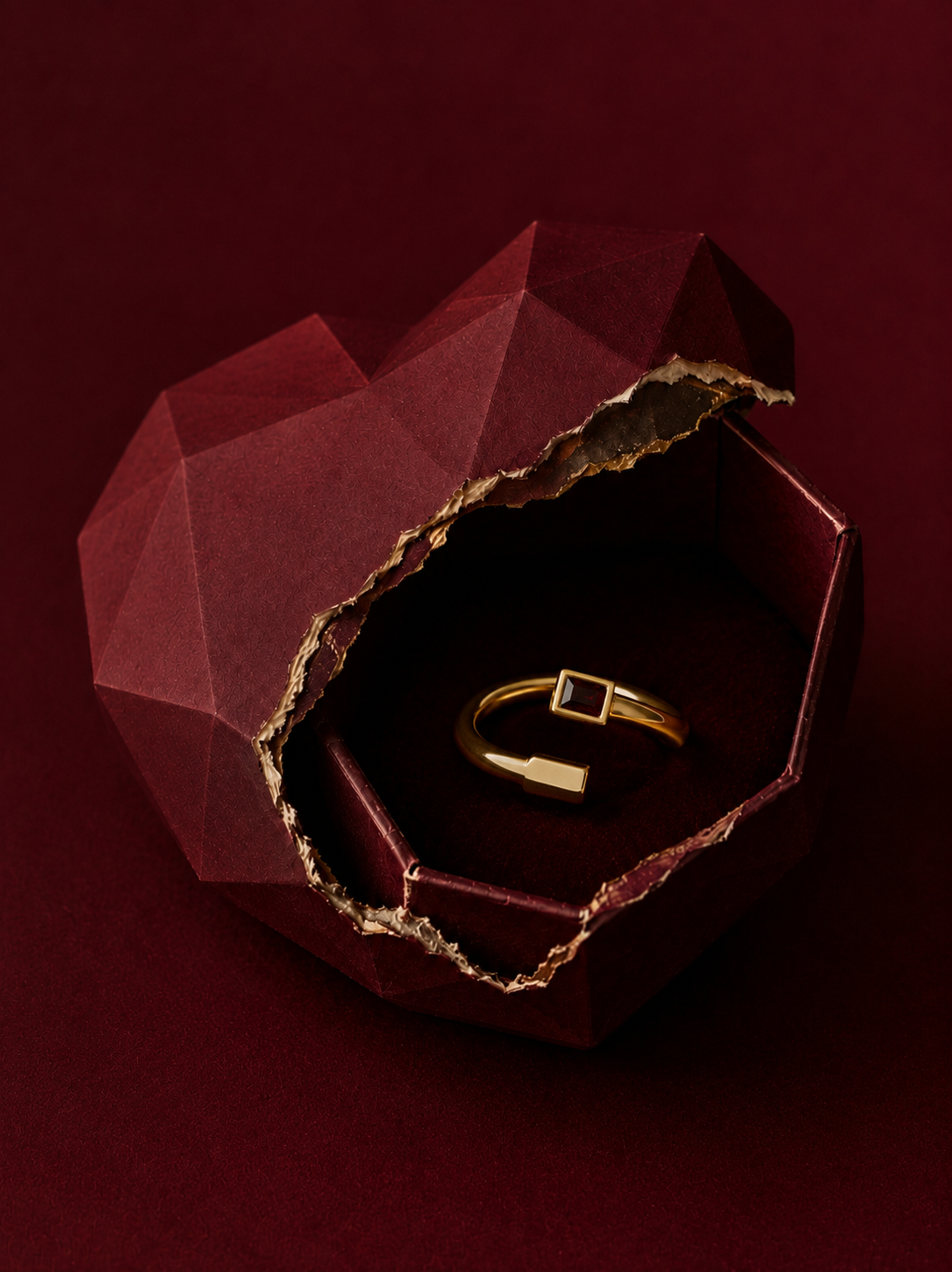 Coffret cœur facetté rouge ouvert révélant bracelet et bague en or sur fond velours bordeaux, Saint-Valentin