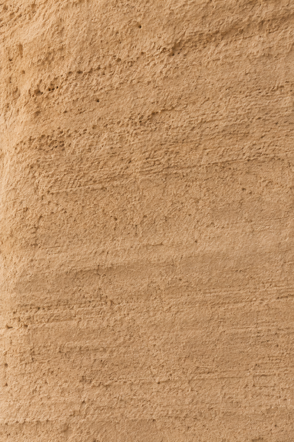 Macro texture mur de plâtre ocre sable – surface rugueuse, stries horizontales, fond neutre chaud