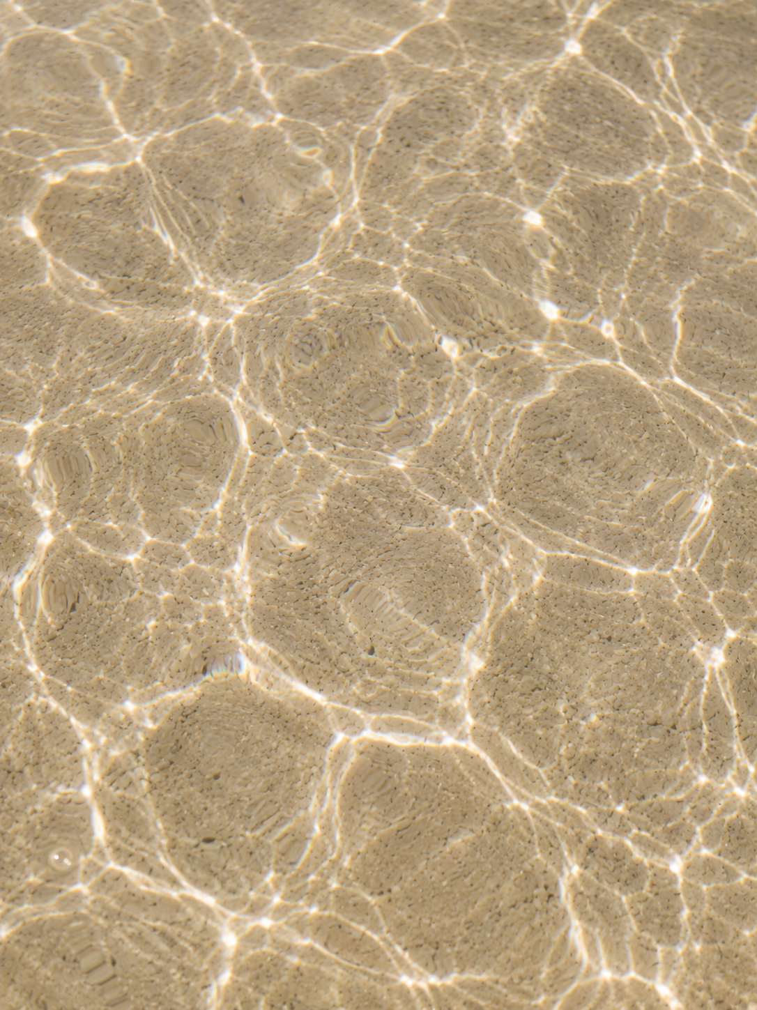 Vue de dessus fond de mer peu profonde – reflets de lumière sur sable, miroitement aquatique