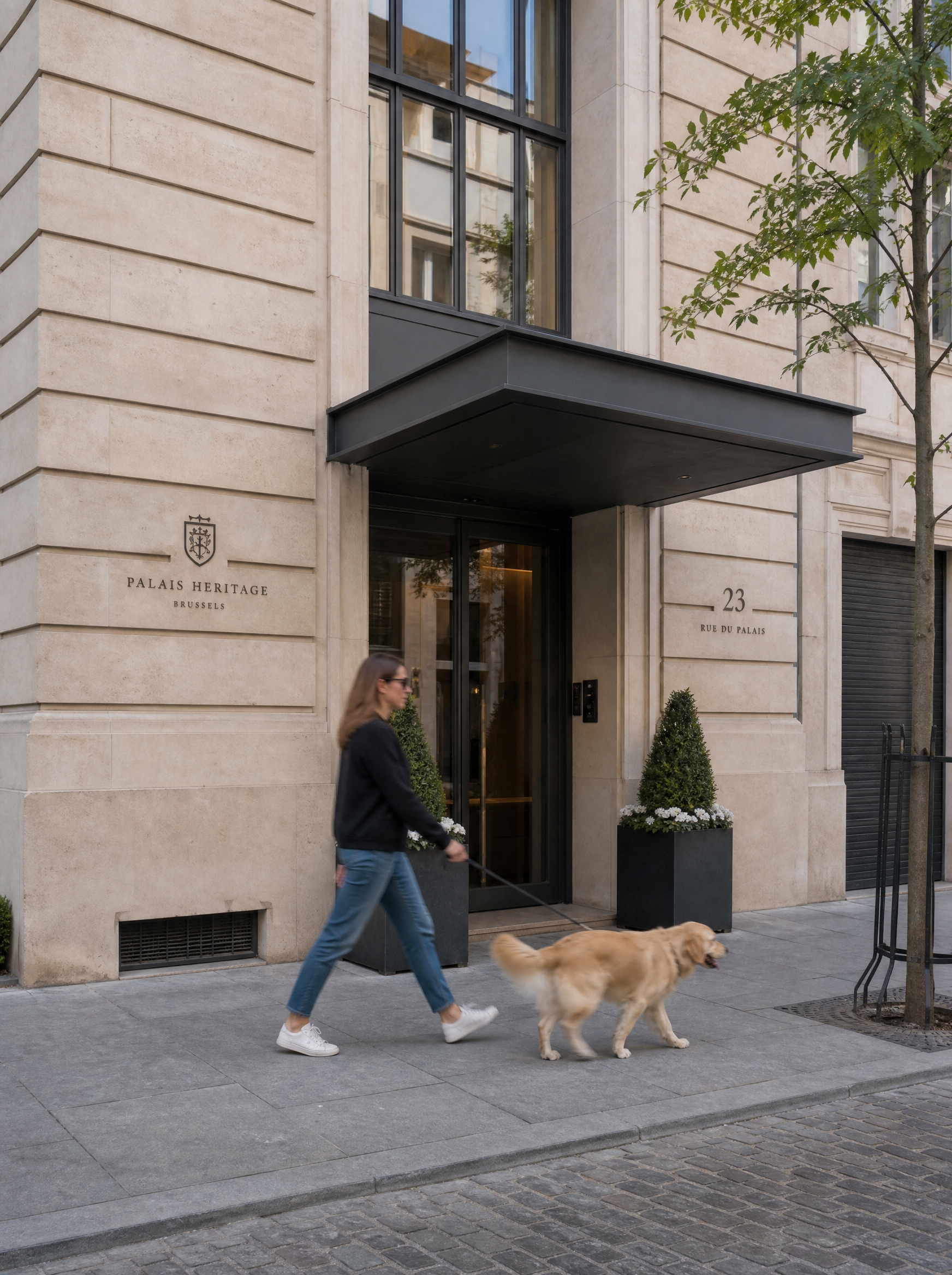 Femme promenant son golden retriever devant la façade de l'agence Palais Heritage Brussels au 23 rue du Palais