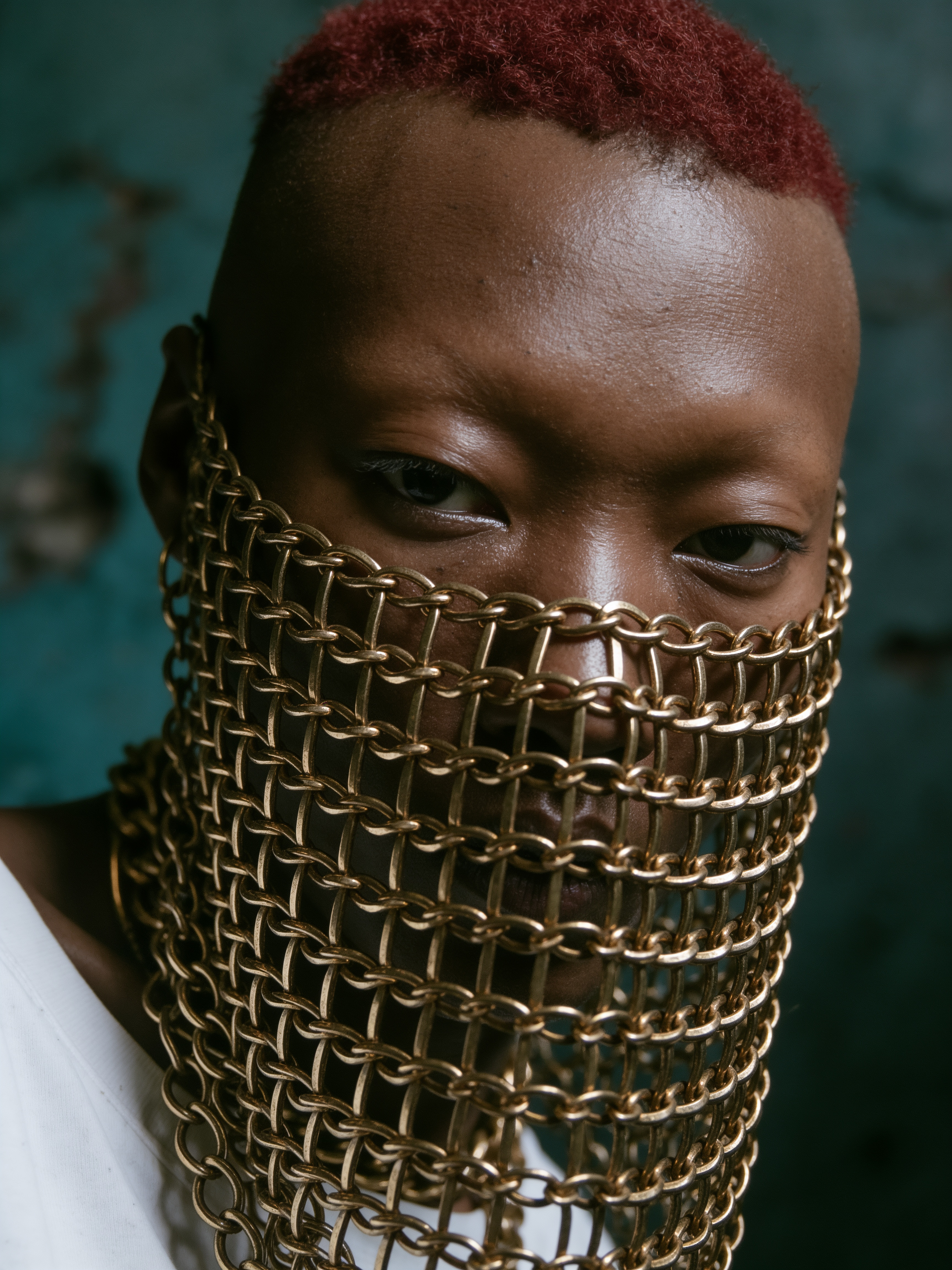 Gros plan du visage d'un homme noir caché derrière un voile de mailles de chaînes dorées