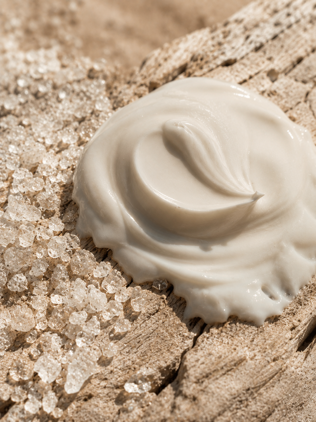 Macro dôme de crème blanche sur bois flotté craquelé – cristaux de sel, texture cosmétique