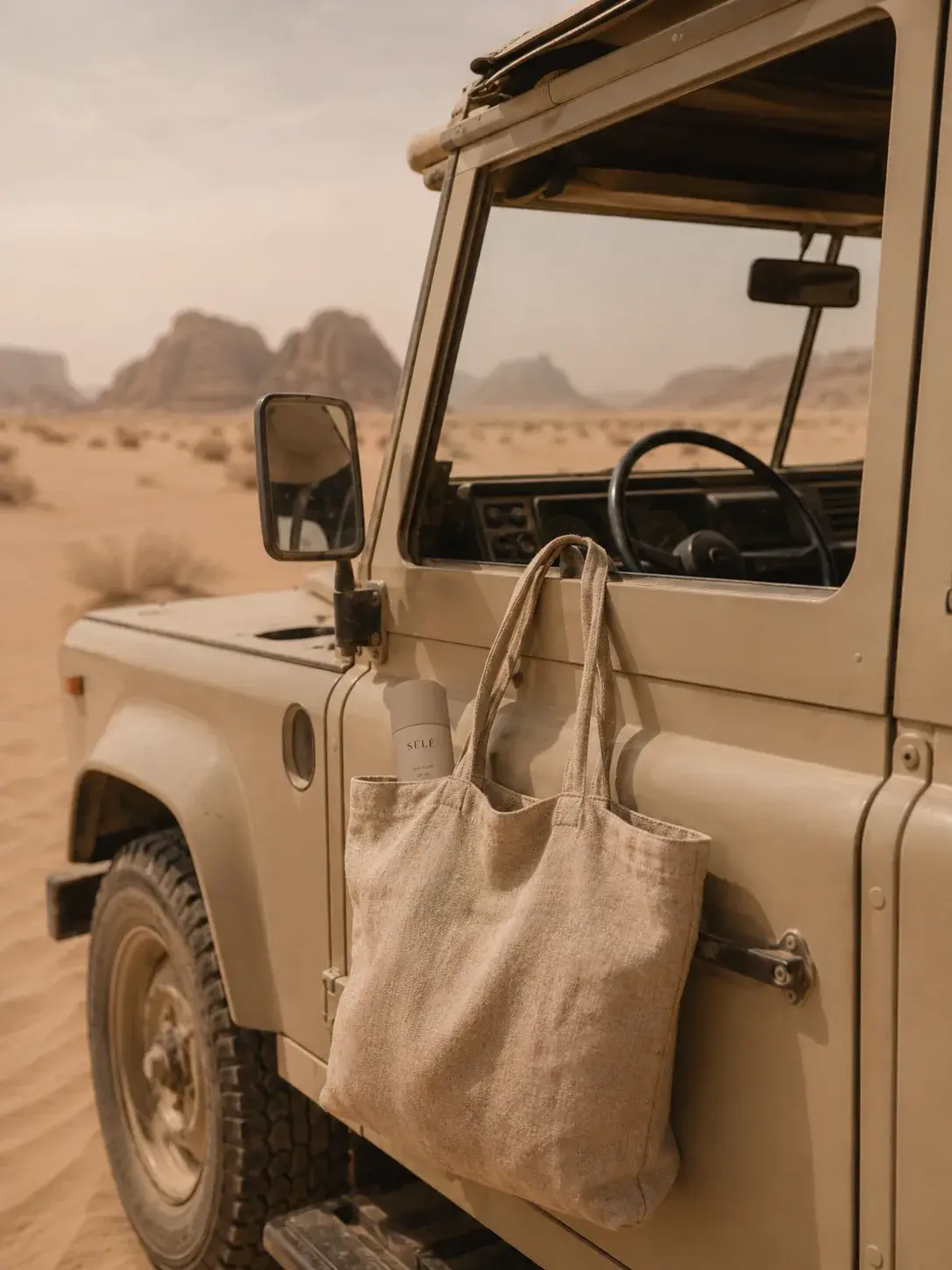 4x4 vintage beige dans le désert – tote bag lin à la portière, flacon soin, Wadi Rum, aventure