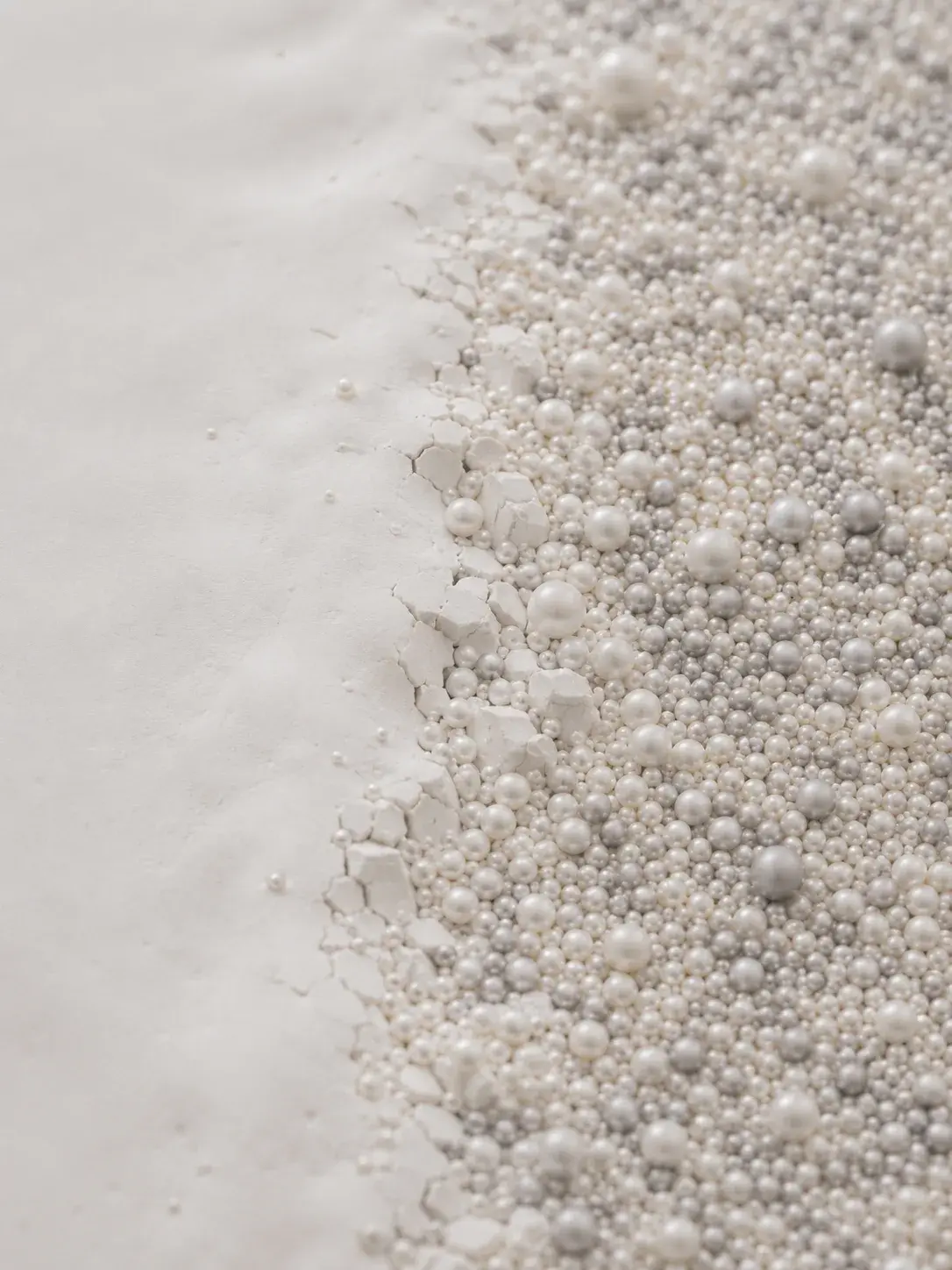 Accumulation de perles de tailles variées à la lisière d'un plan blanc lisse, frontière nacrée vue macro