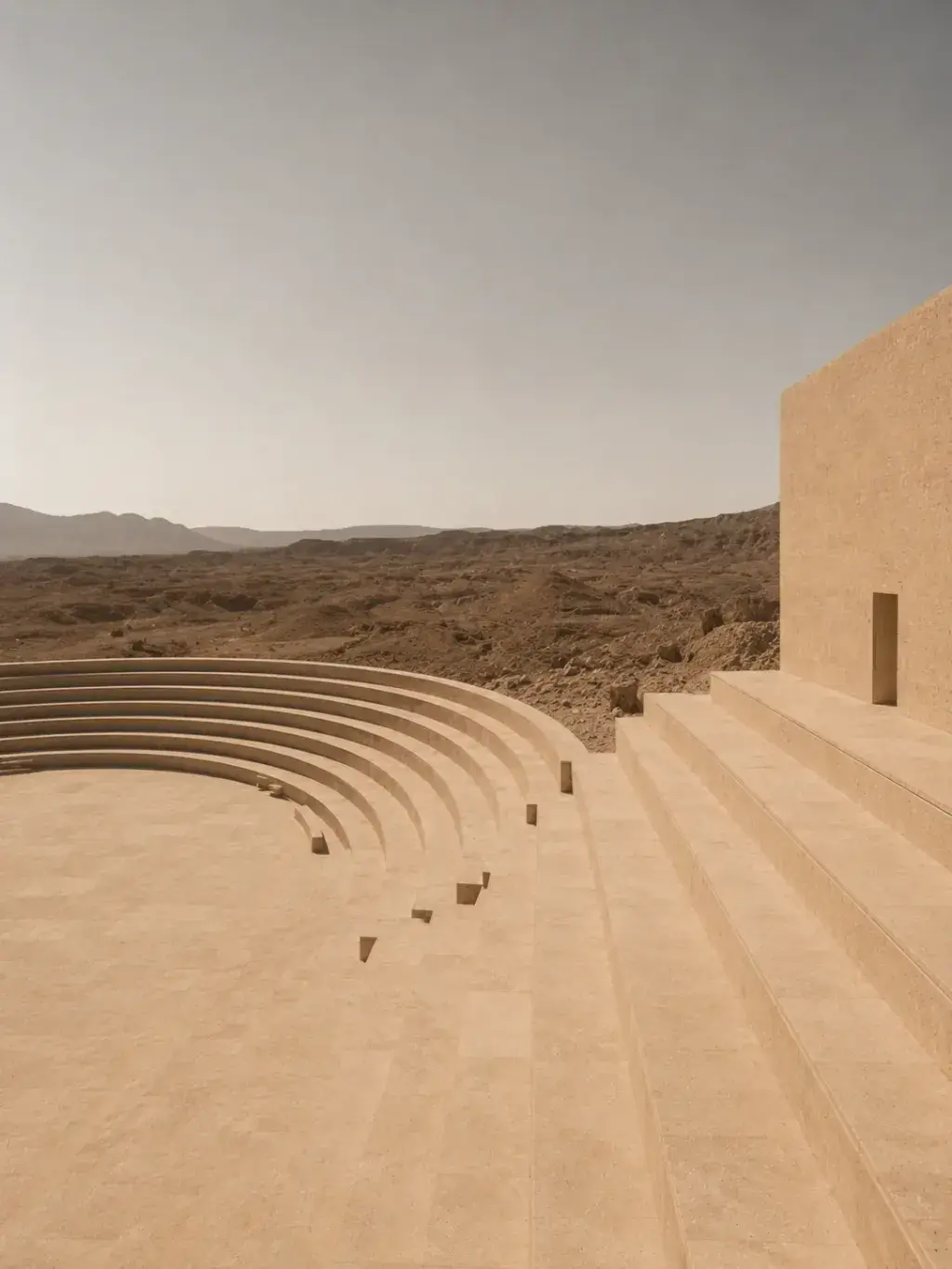 Amphithéâtre en pierre calcaire beige dans le désert – marches incurvées, montagnes, ciel pâle