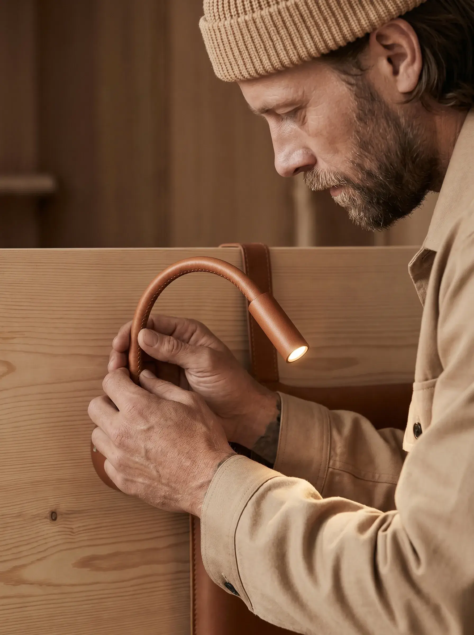Artisan posant une liseuse flexible en cuir et laiton sur un panneau en bois
