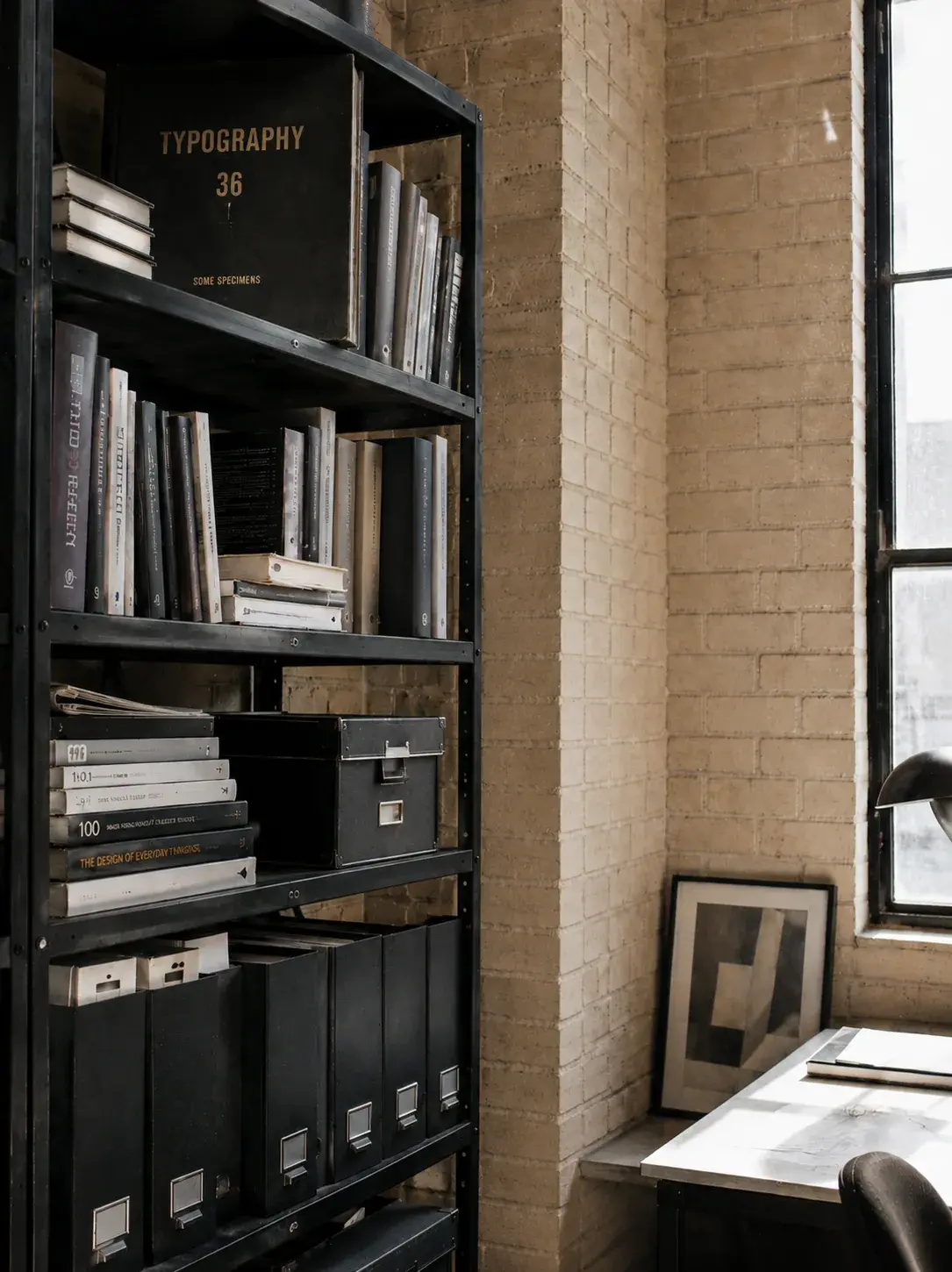 Bibliothèque studio – étagère livres de design, mur brique