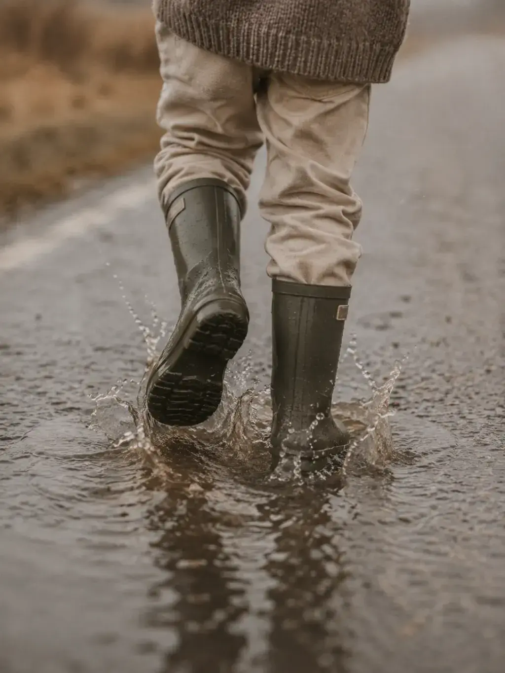 Bottes en caoutchouc éclaboussant dans une flaque de pluie