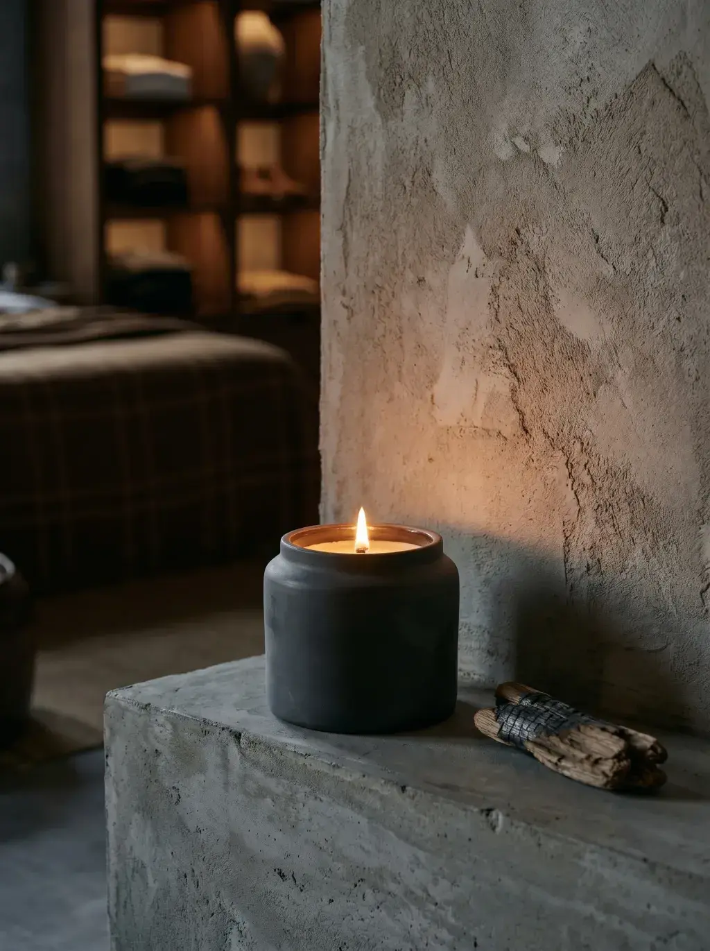 Bougie en céramique noire allumée sur un bloc de béton dans une boutique sombre