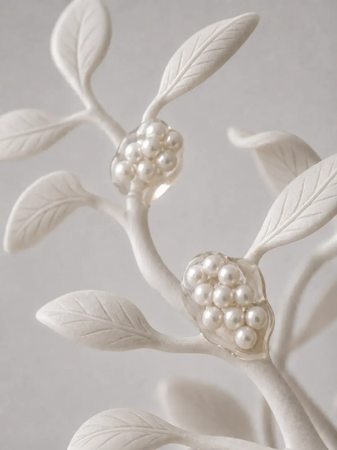 Branche sculptée blanche avec feuilles moulées et grappes de perles formant des fruits nacrés