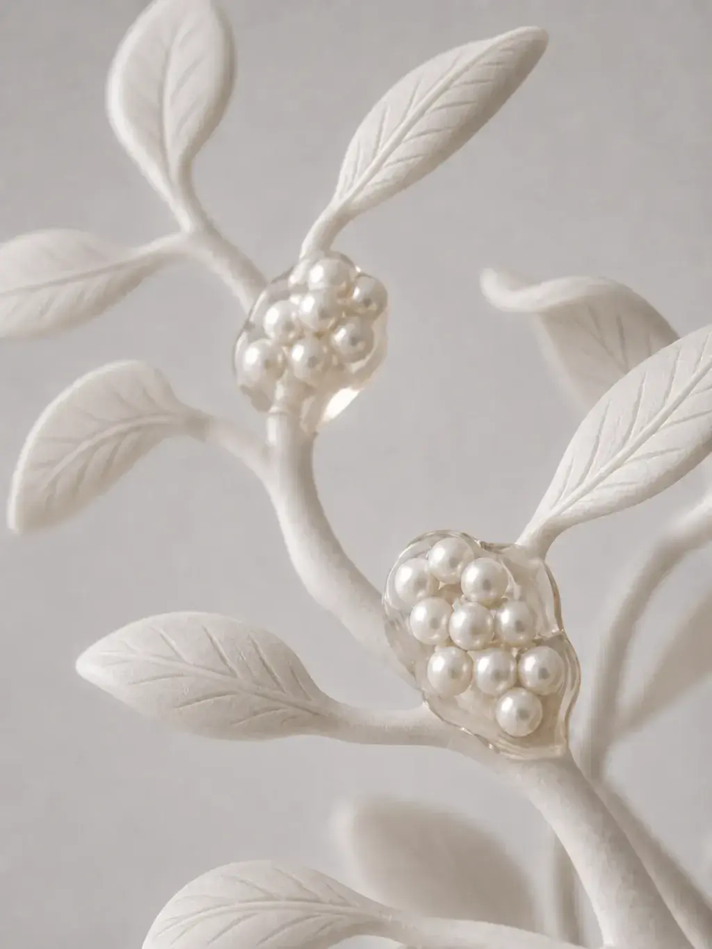 Branche sculptée blanche avec feuilles moulées et grappes de perles formant des fruits nacrés