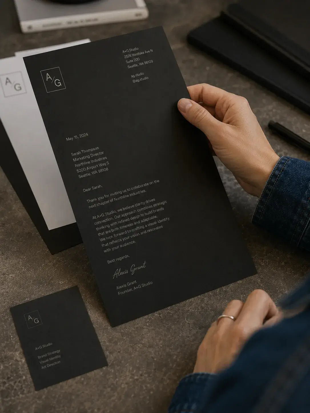 Carte de visite et lettre noires – identité sombre, surface béton