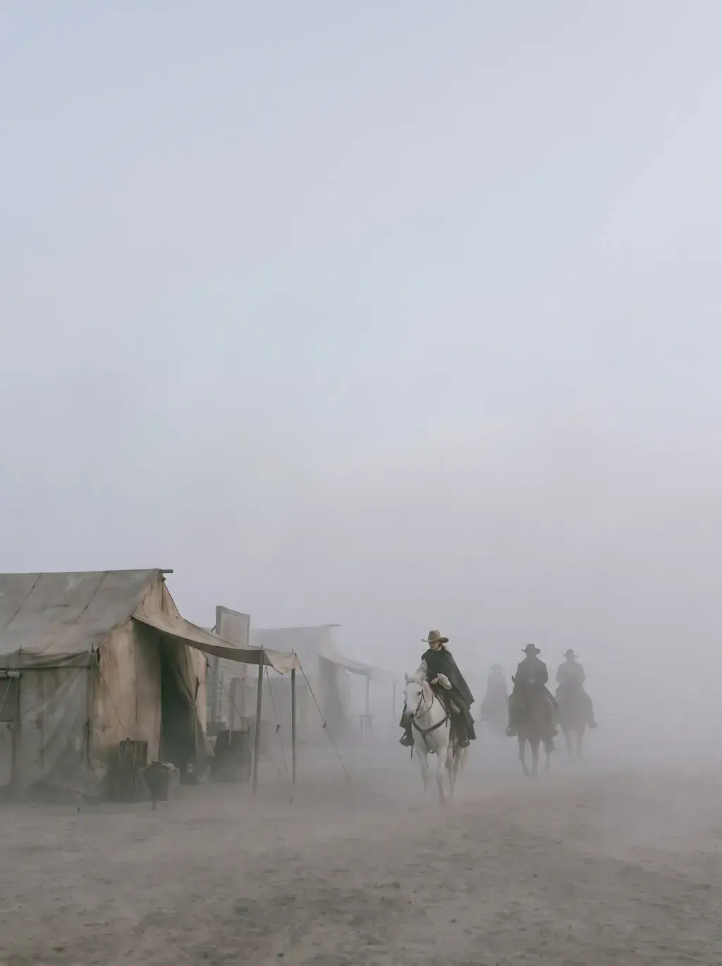 Cavaliers en capes entrant dans un village fantôme désertique enveloppé de brume épaisse