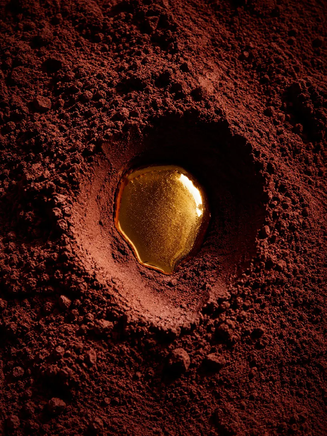 Cavité circulaire dans poudre de cacao avec goutte de caramel – vue de dessus, macro, texture