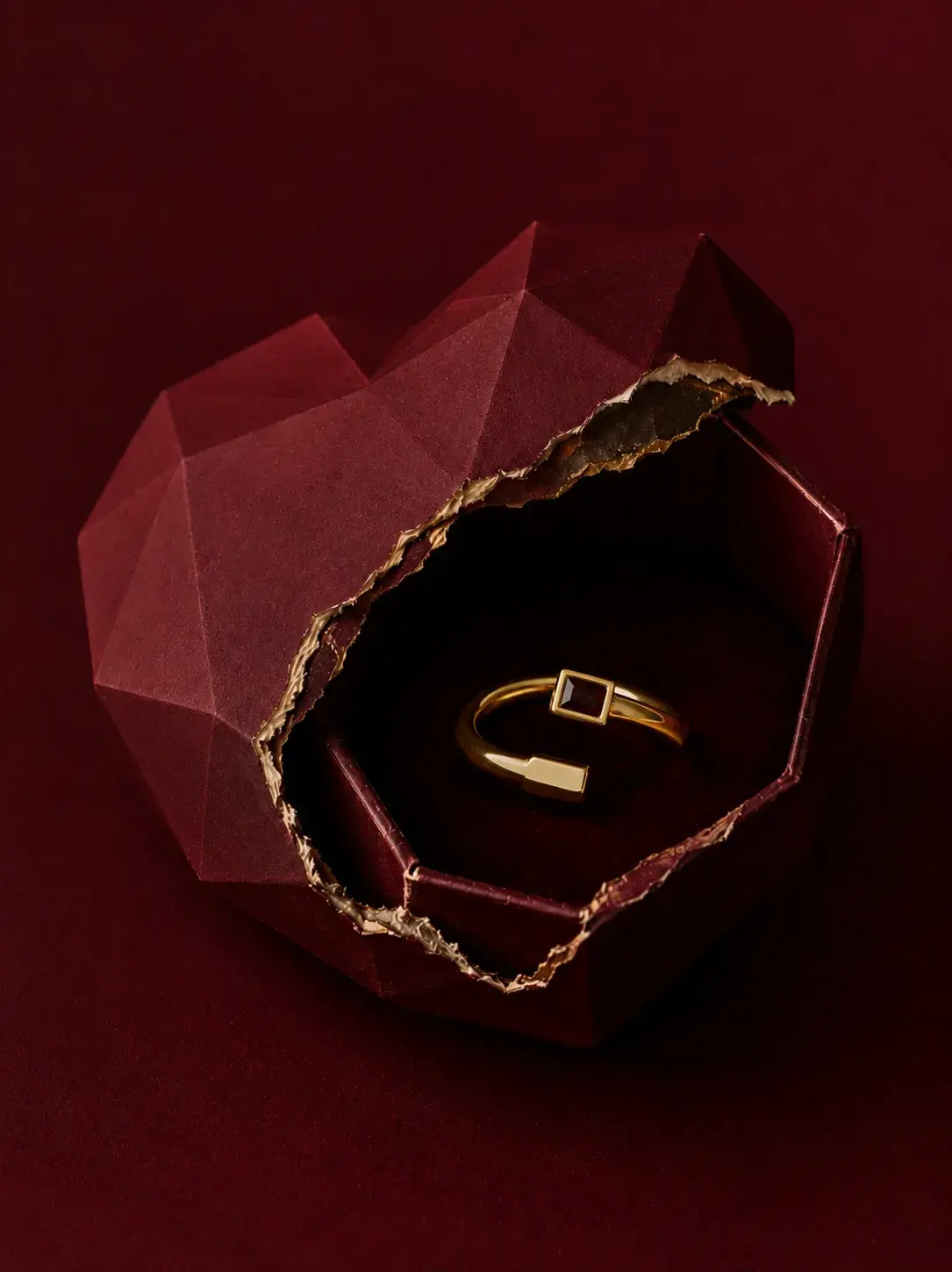 Coffret cœur facetté rouge ouvert révélant bracelet et bague en or sur fond velours bordeaux, Saint-Valentin