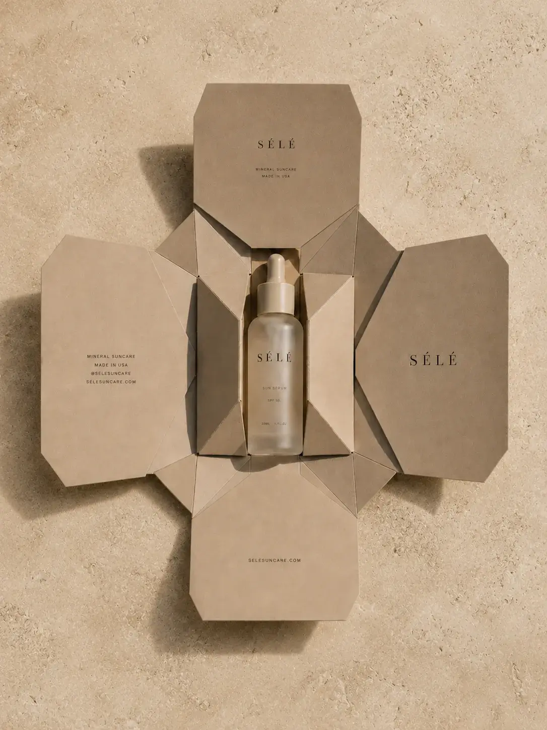 Coffret kraft déplié en étoile – flacon sérum au centre, vue de dessus, travertin, ombre graphique
