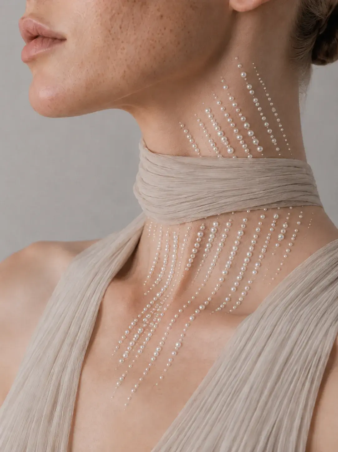 Décolleté féminin avec fils de perles partant en éventail depuis l'oreille vers l'épaule, bijou corporel