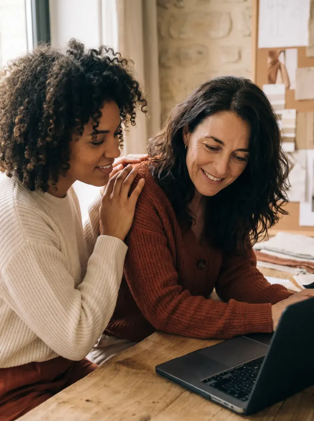 Deux créatrices se soutenant mutuellement penchées sur un laptop dans leur atelier