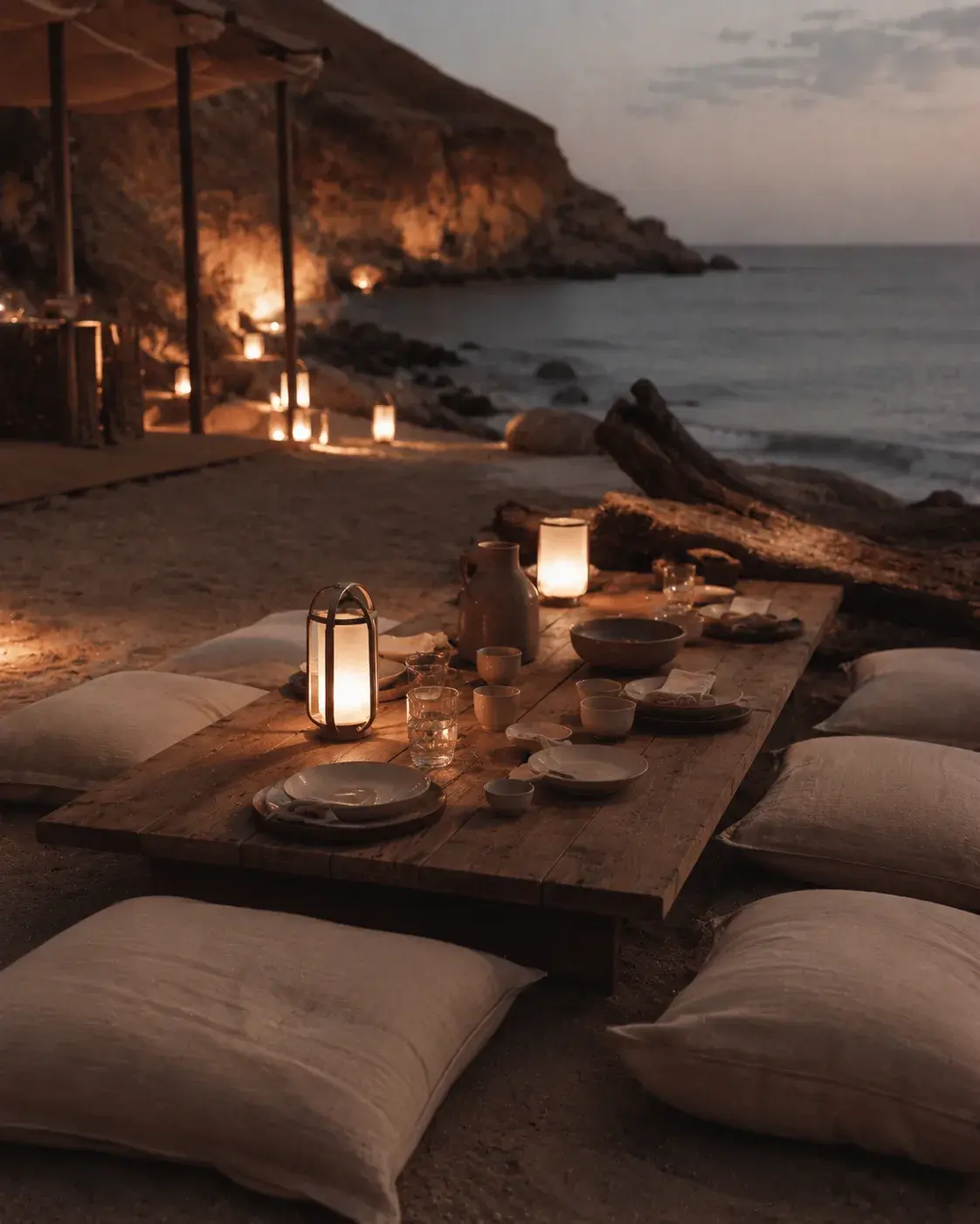 Dîner romantique sur sable de plage au crépuscule – table basse, coussins lin, lanternes