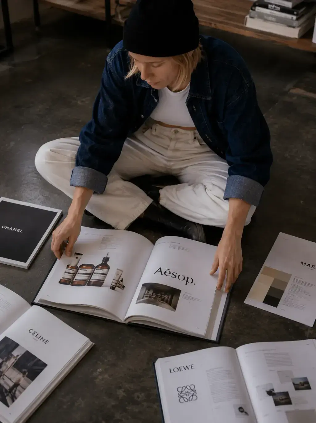Directrice artistique – lecture livres de design, assise au sol, studio