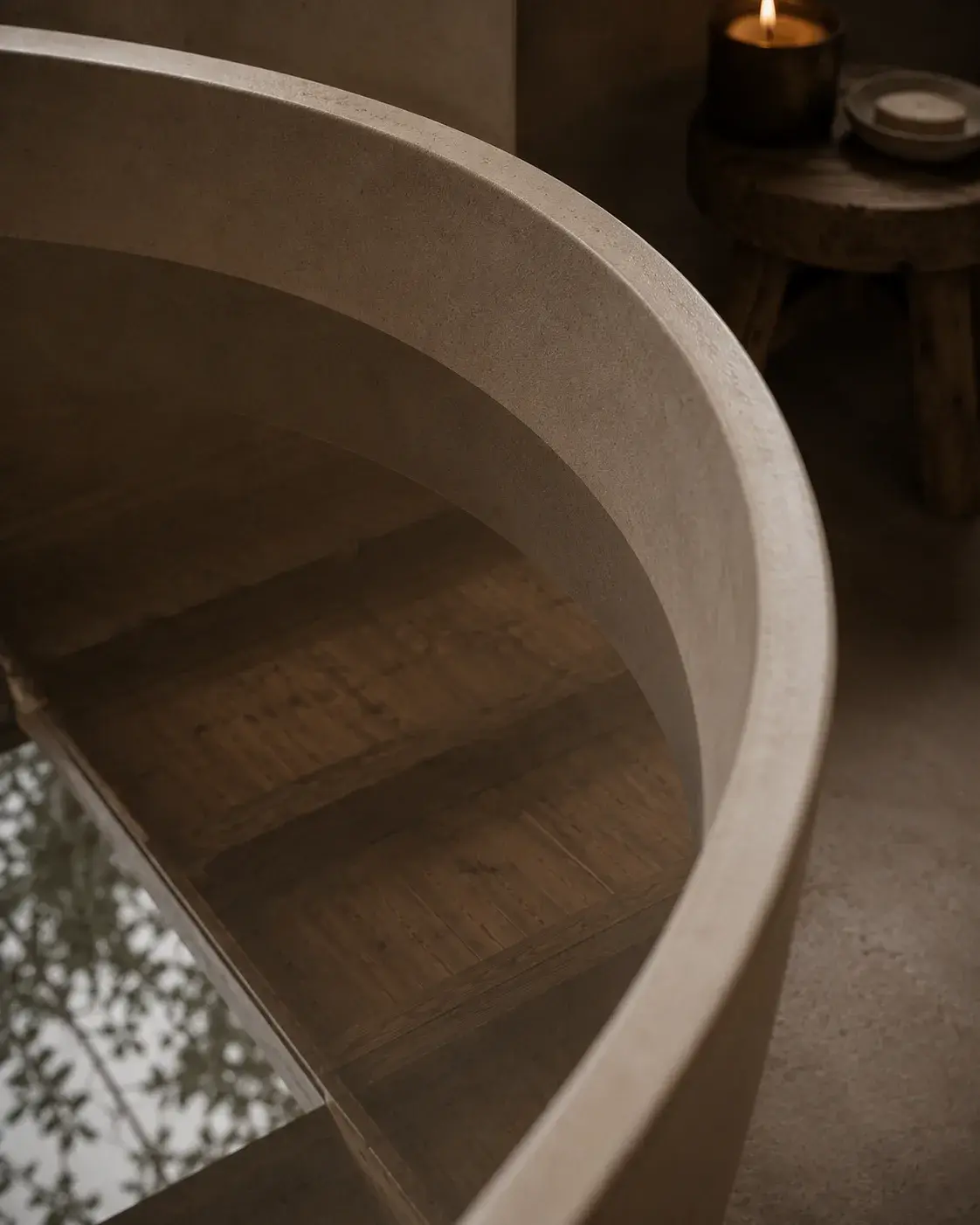 Escalier circulaire en béton poli vu depuis le bord avec bougie sur guéridon et végétation tropicale en fond