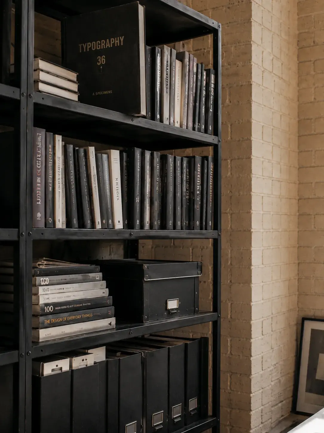 Étagère studio – livres de design, vue rapprochée, mur brique