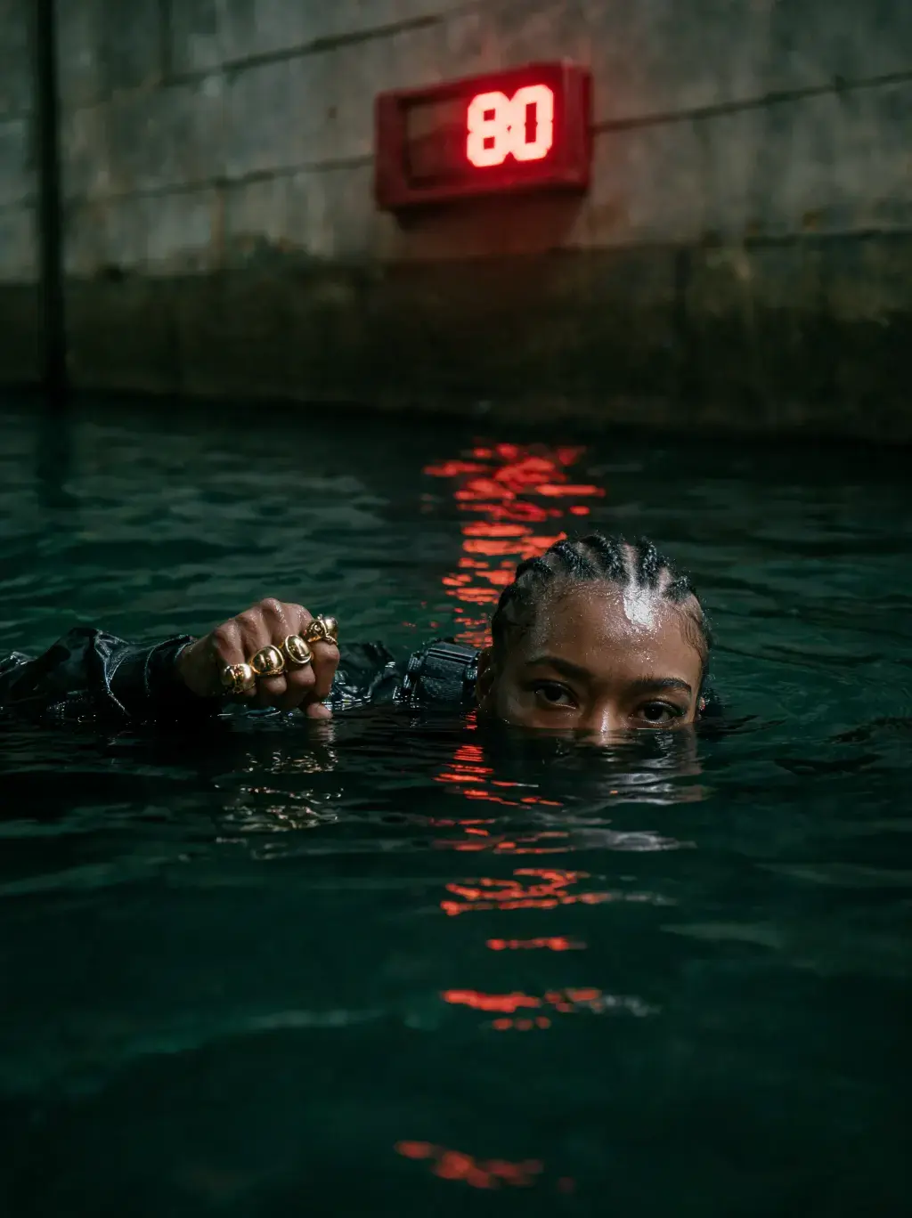 Femme aux tresses immergée dans un canal industriel sous un panneau LED rouge