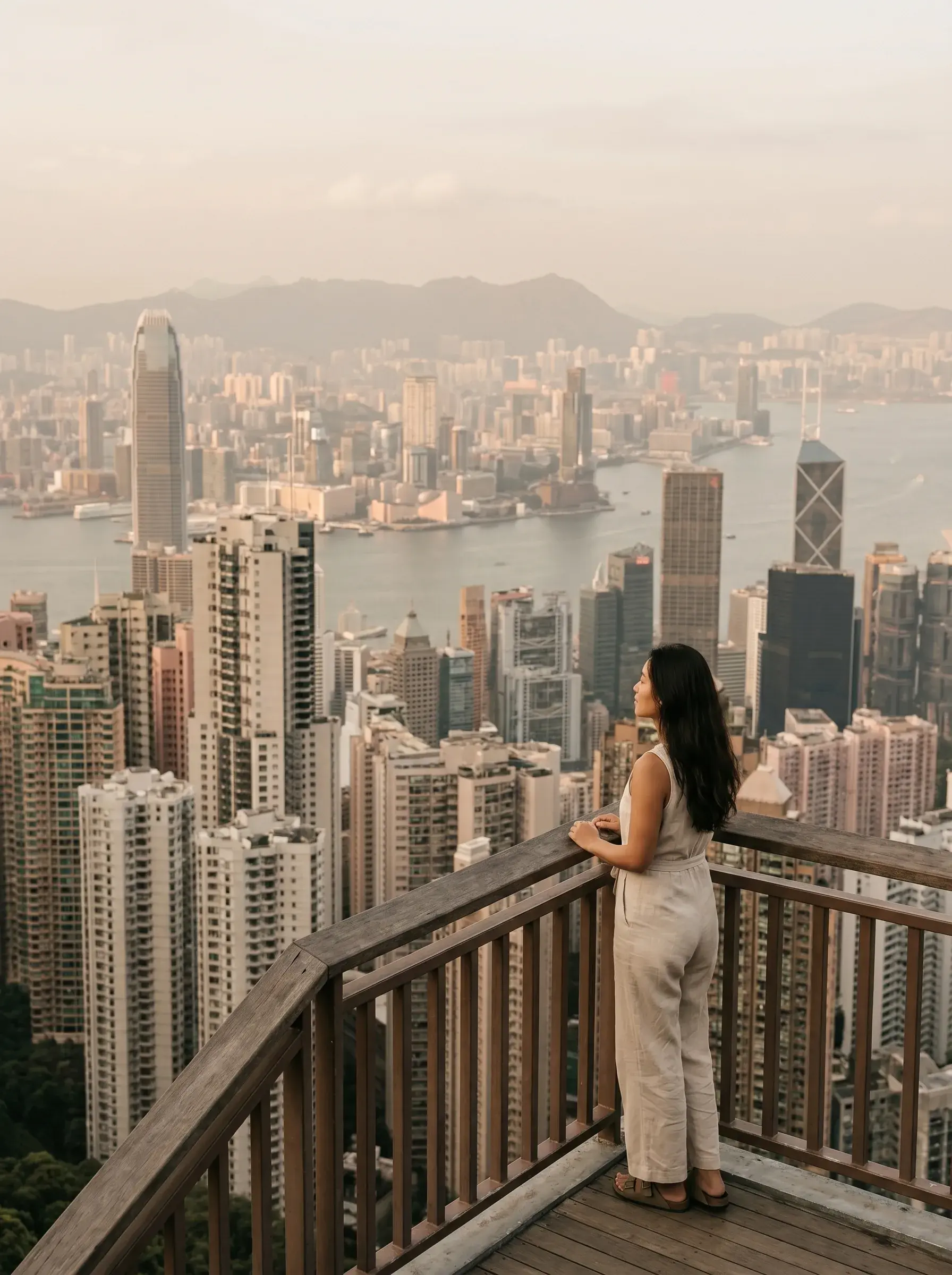 Femme contemplant le skyline de Hong Kong – belvédère Victoria Peak, gratte-ciels, coucher de soleil rose