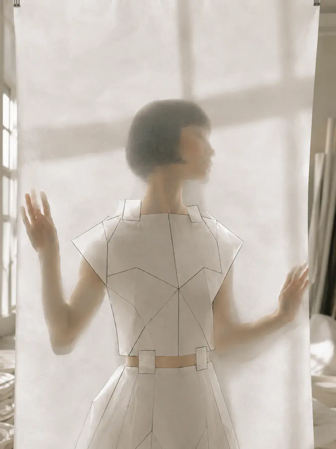 Femme en top origami les mains sur voile translucide – lumière de fenêtre