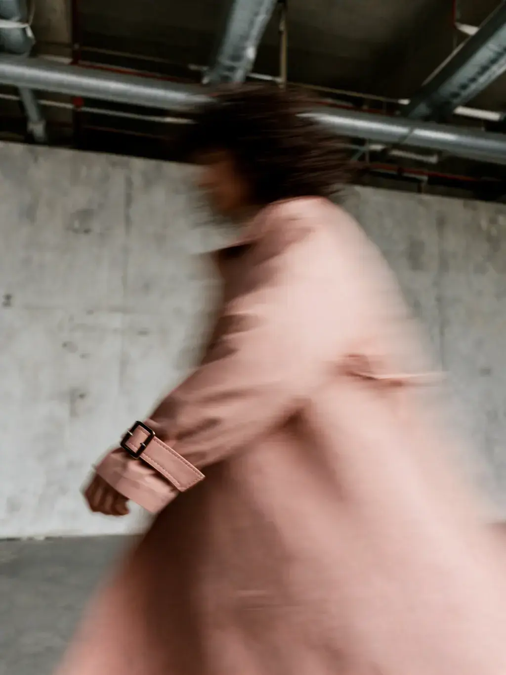 Femme manteau rose saumon en mouvement béton