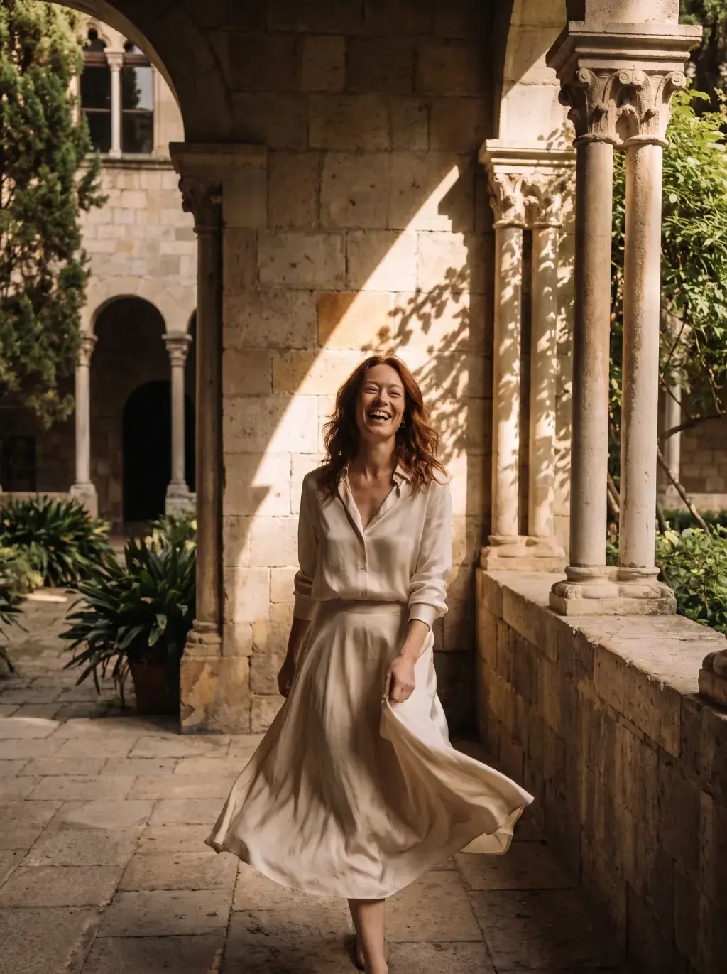 Femme marchant dans un cloître provençal en robe beige au soleil