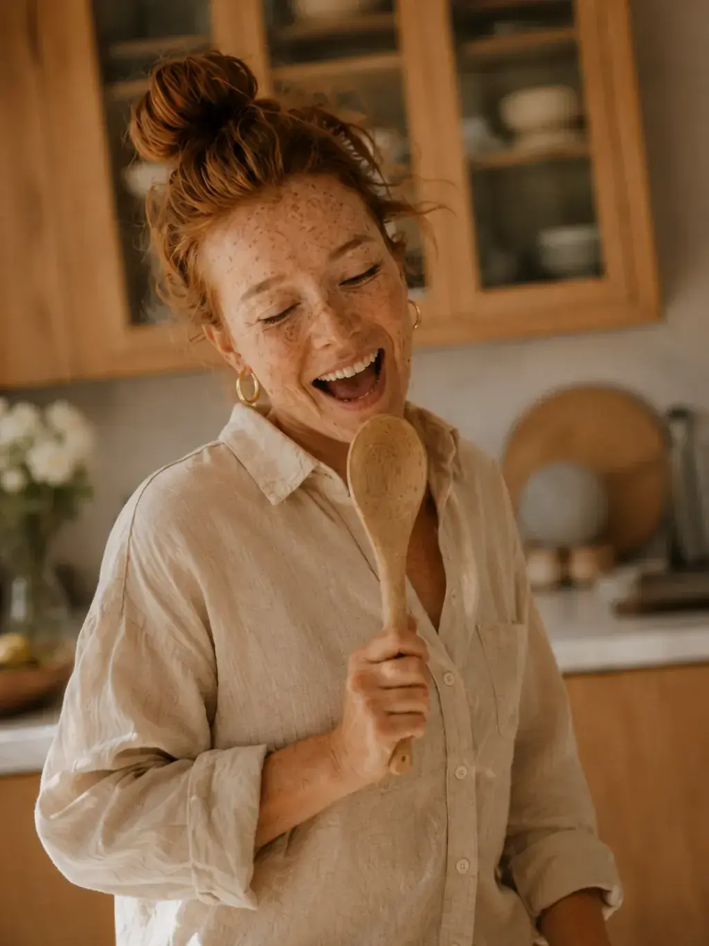 Femme rousse chantant dans sa cuisine avec une cuillère en bois