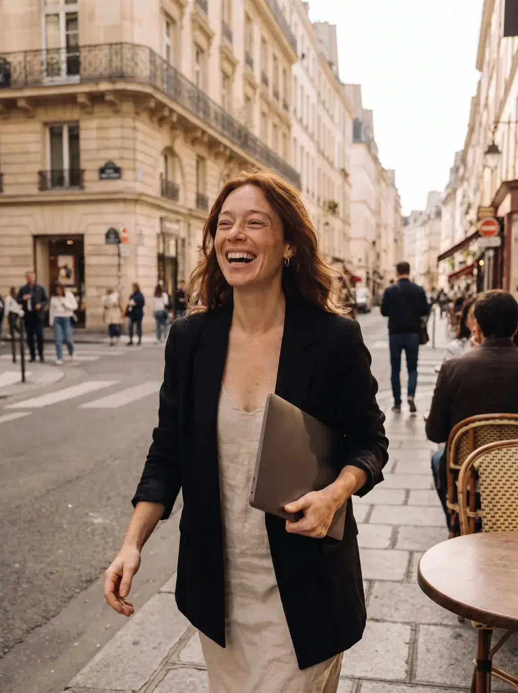 Femme rousse marchant dans une rue parisienne avec son laptop