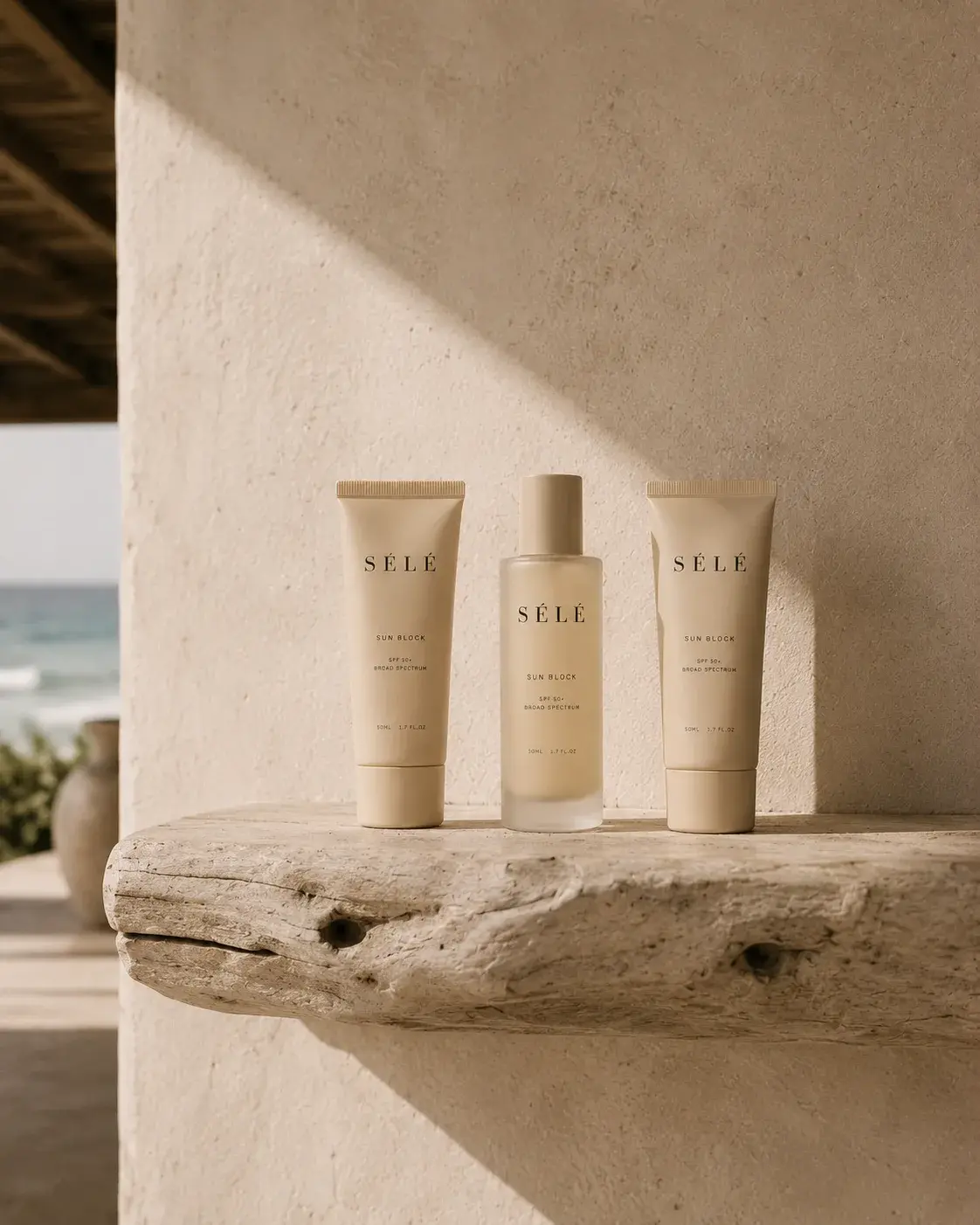 Gamme de 3 produits soin sur étagère bois flotté – mur plâtre blanc, vue mer, ombre végétale