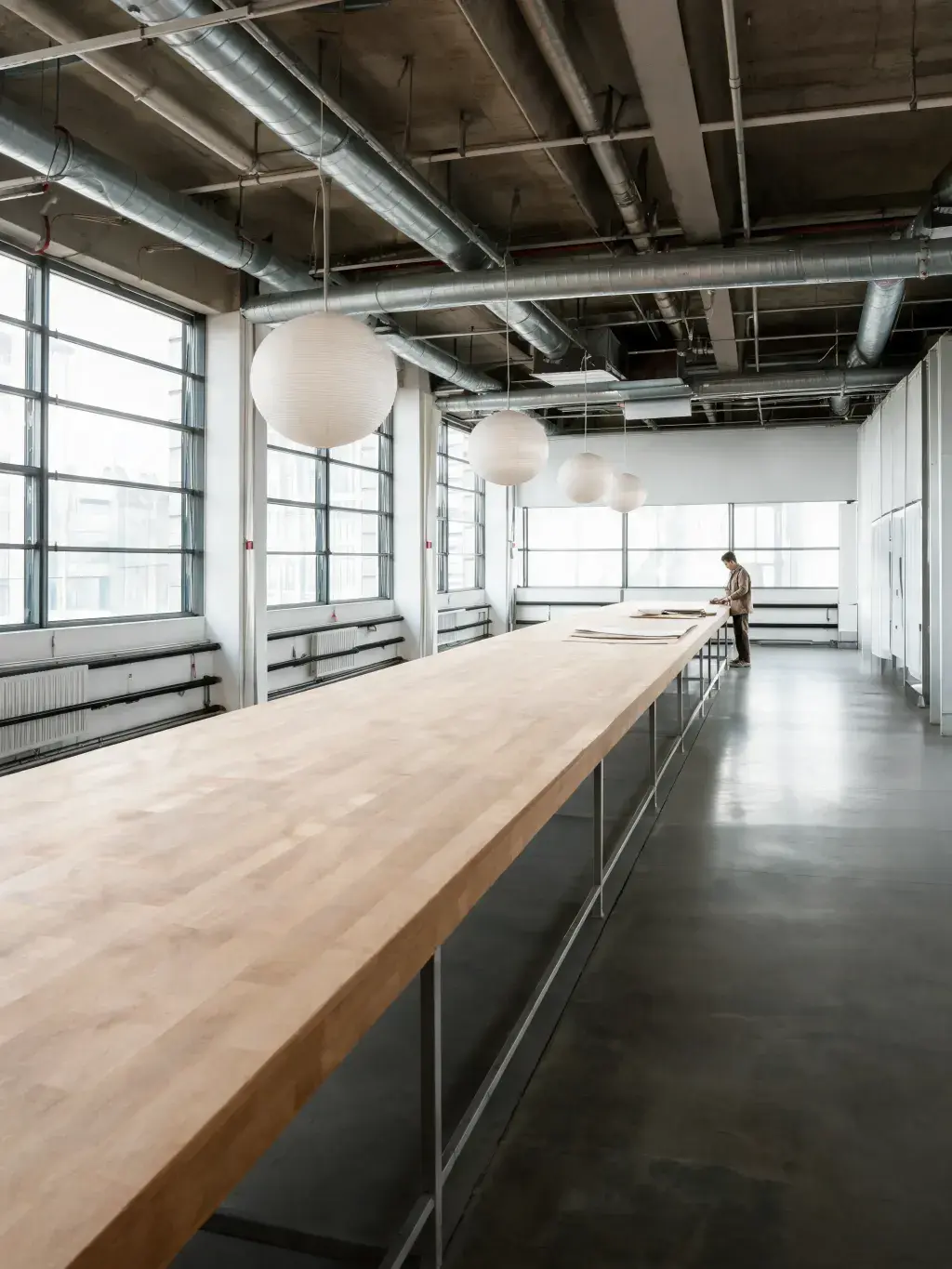 Grande table de coupe bois – atelier lumineux, lampes globe, fenêtres panoramiques, loft mode