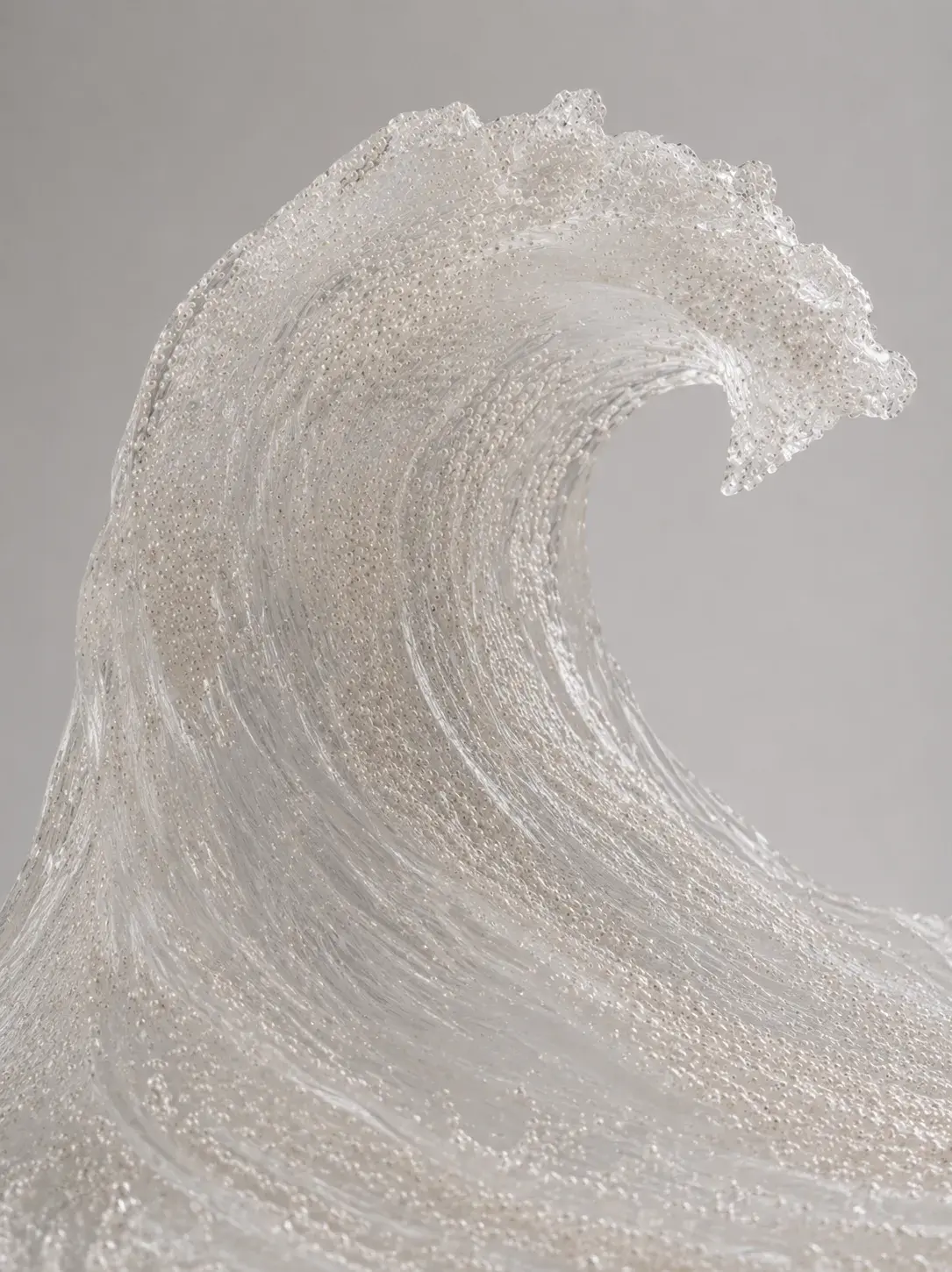 Grande vague sculptée en micro-perles et cristaux translucides, détail de la crête déferlante, fond gris