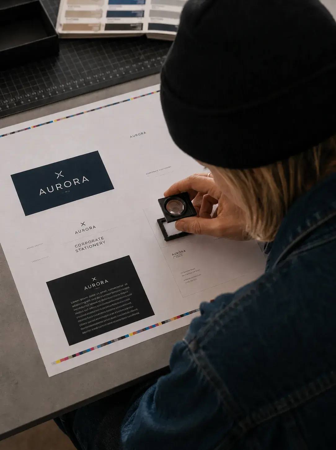 Graphiste – loupe sur maquette imprimée, nuanciers, contrôle qualité