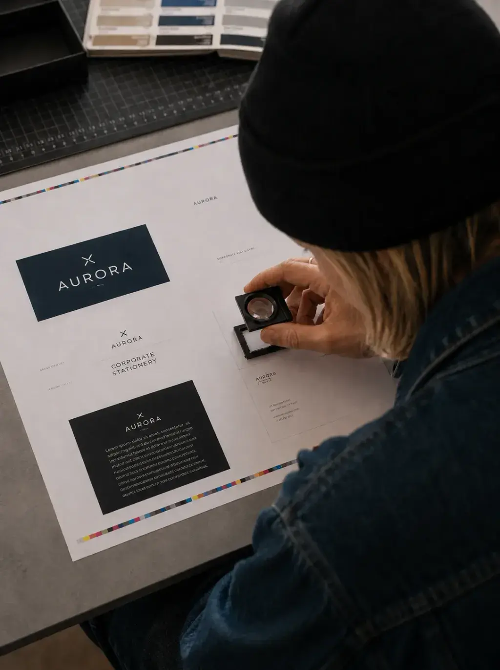 Graphiste – loupe sur maquette imprimée, nuanciers, contrôle qualité