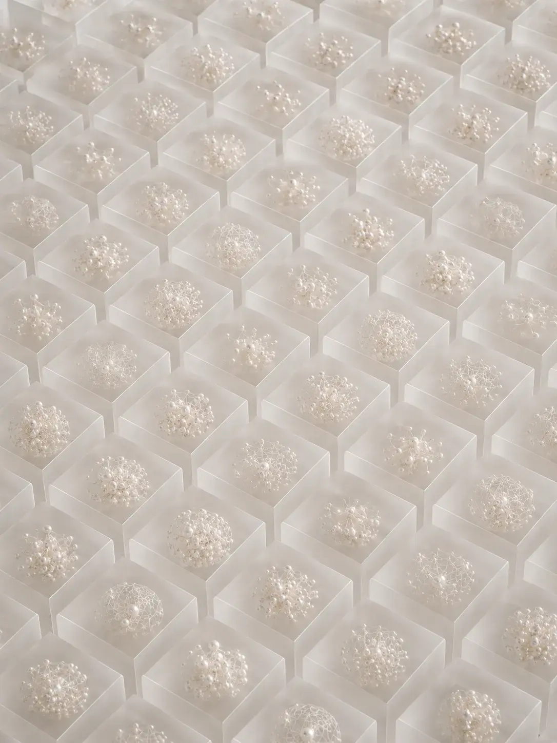 Grille de cubes en résine givrée contenant chacun un agrégat de perles, vue plongeante