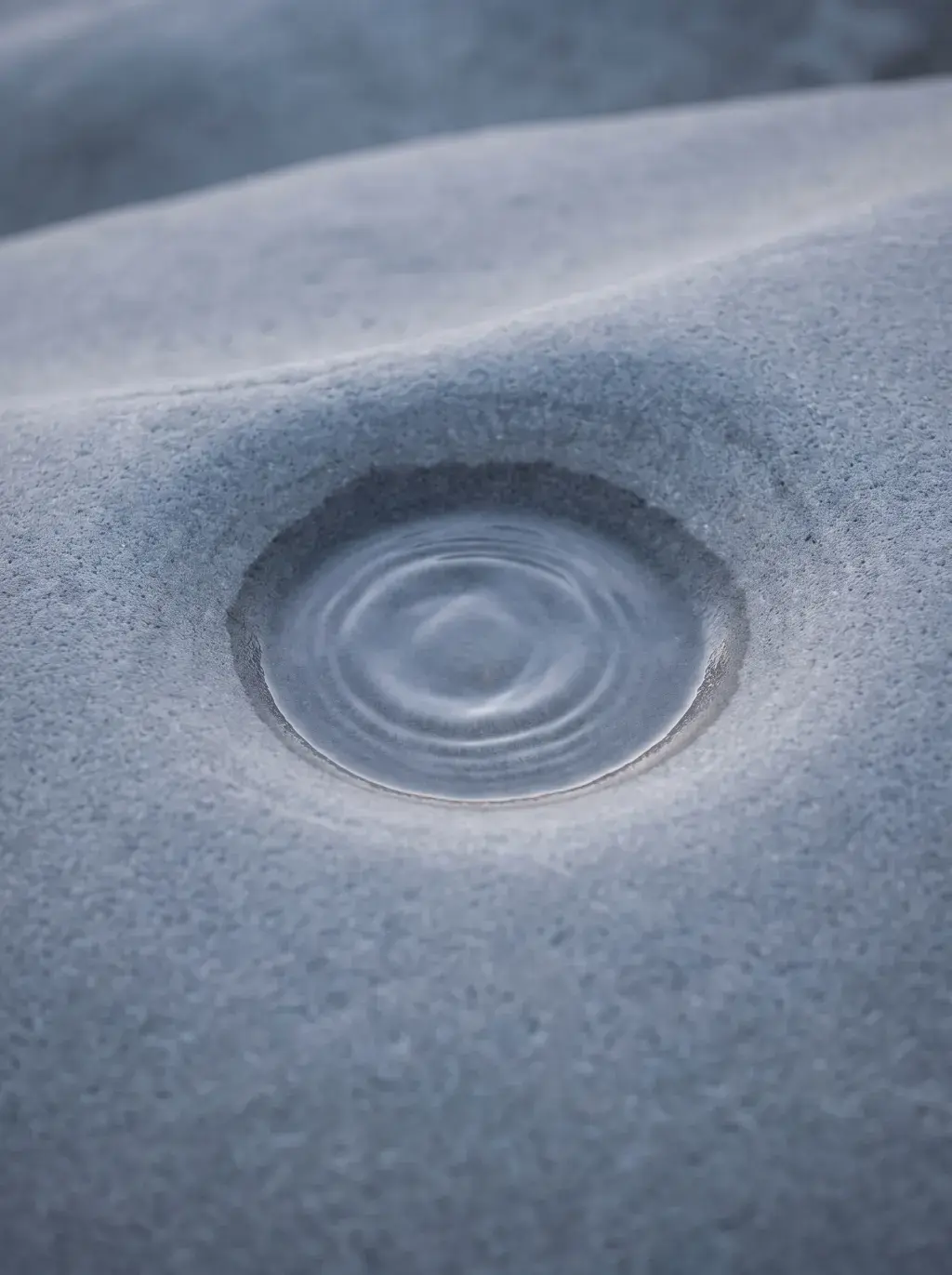 Gros plan d'une flaque d'eau dans le sable avec des cercles concentriques